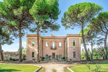 Pink masseria behind tall trees