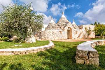 Coned trullo amid lawns with olive tree