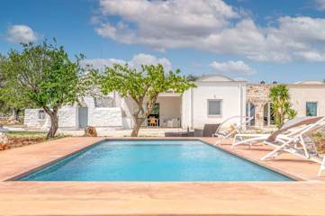 Swimming pool in front of two trees and a white villa