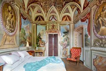 Unmade bed in a room with frescoed walls