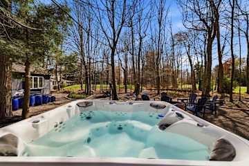Drop into the hot tub at water level and you're looking straight out at the chairs, the trees, and the golf lawn beyond.