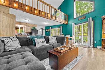 Enjoy a cozy living room with high ceilings, natural light, a comfy couch, and an open-plan layout perfect for relaxing! 🛋️🌞🏡