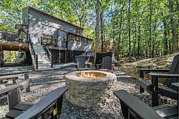 Pull your chair right up to the stone fire pit and watch the actual flames — the wooded Poconos night closes in around you, and the only agenda item is staying warm and talking too late.