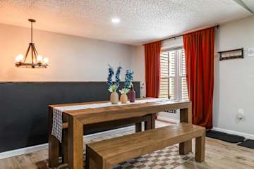 A farmhouse dining room with a solid wood table, bench seating for 8+, and a warm chandelier — the ideal setup for group meals at this Pocono vacation rental.