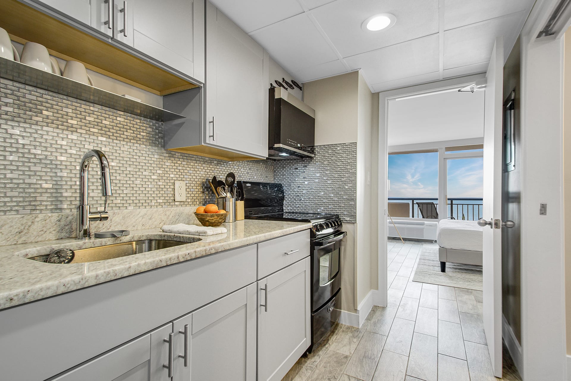 Modern kitchen with sleek cabinetry and a stylish blue-tile backsplash, fully equipped for your culinary needs. Just steps from the bedroom, this space offers convenience and functionality, allowing you to enjoy meals with a stunning ocean view.