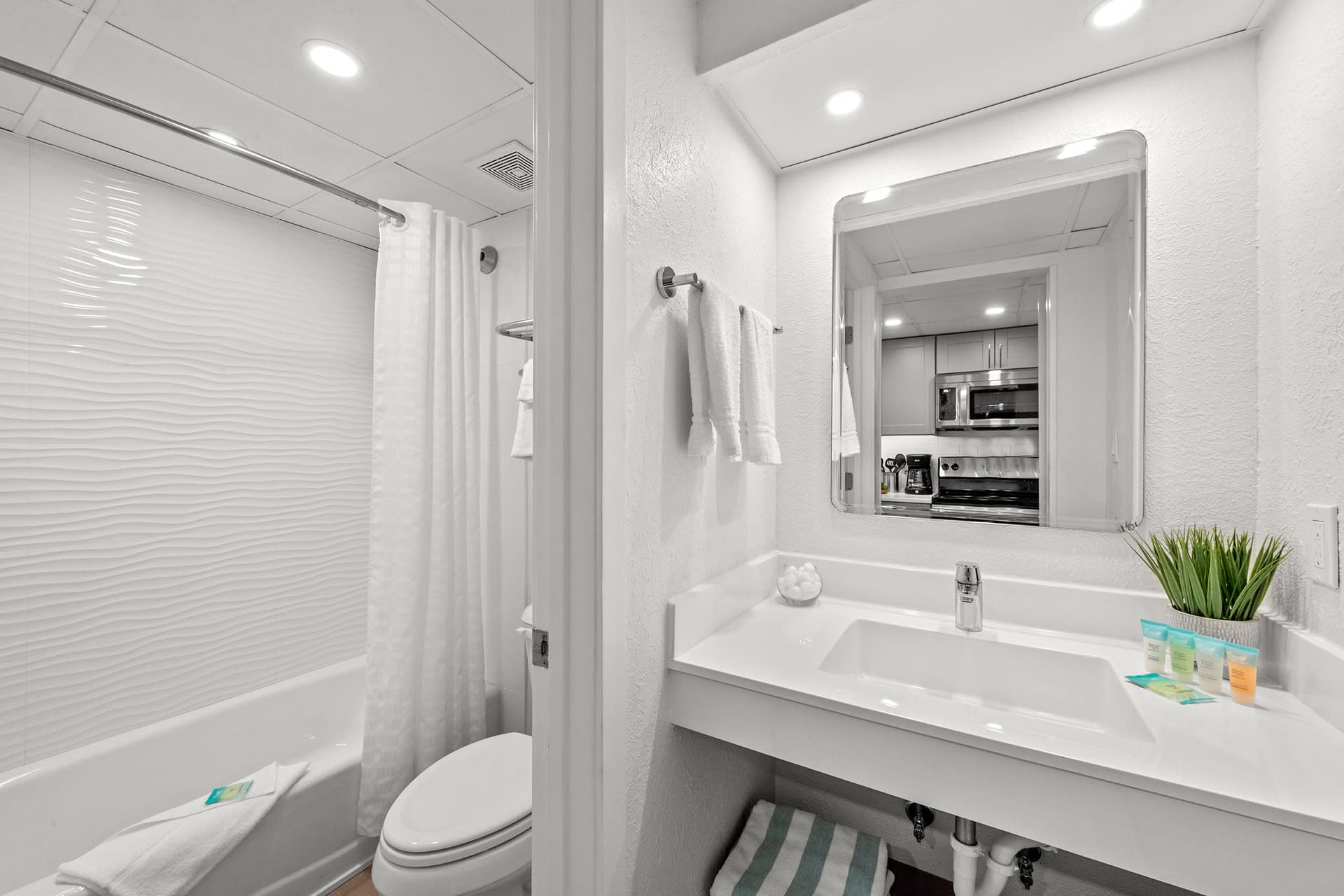 Clean and modern bathroom with a shower/tub combo and granite countertop vanity. 
