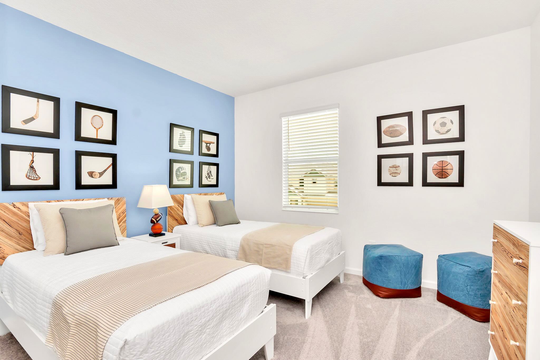 Fun Twin Bedroom Featuring Stylish Blue Wall, Art Gallery Accents, And Comfortable Beds