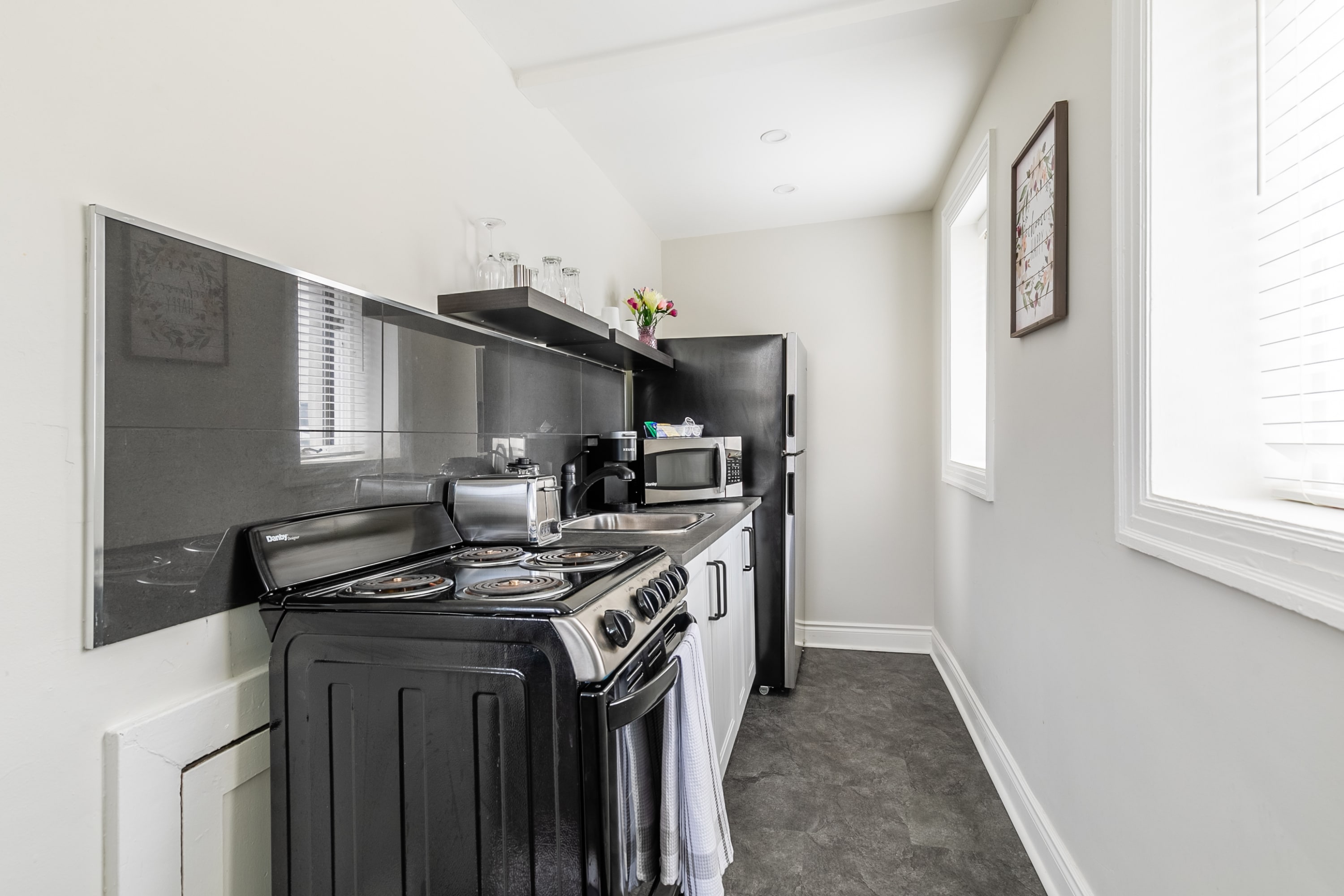 Fully Equipped Kitchen With Modern Appliances Including Stove, Microwave, And Refrigerator