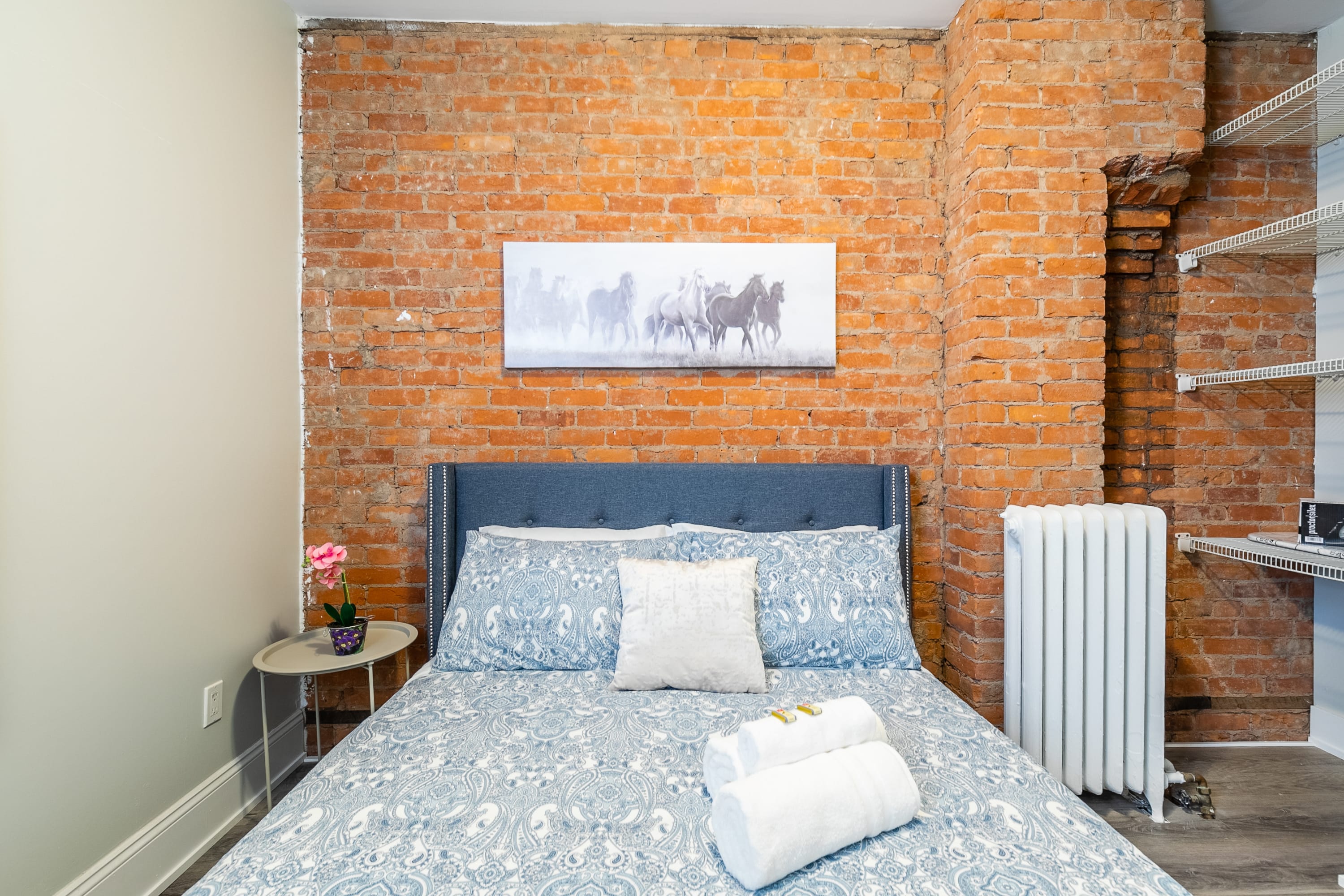 Queen Bed With Elegant Bedding And A Stunning Exposed Brick Wall Backdrop