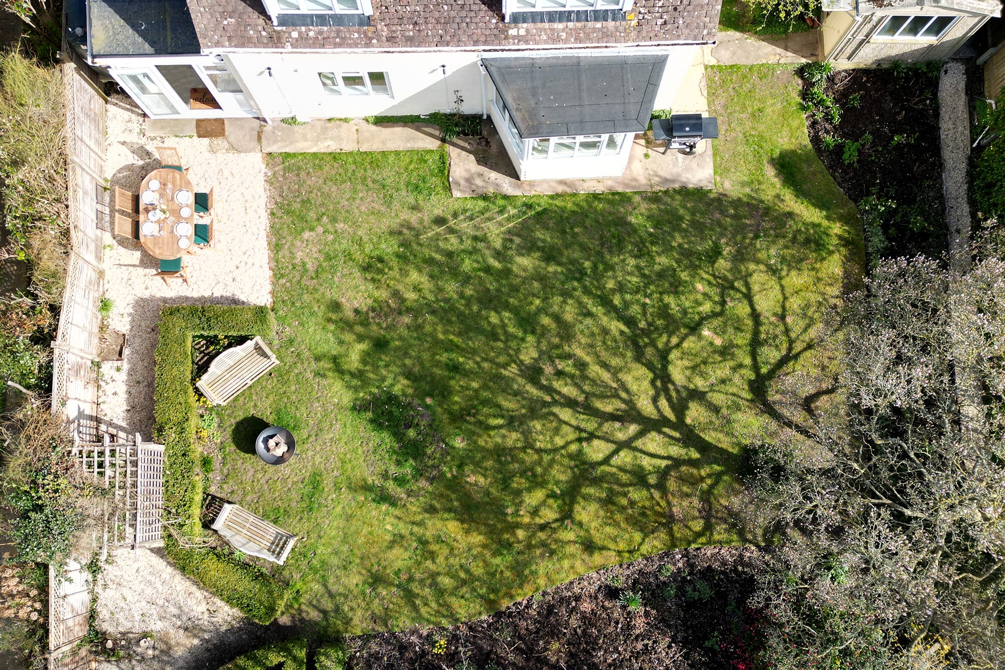 There is bench seating by the fire pit, outdoor dining furniture and a gas BBQ.