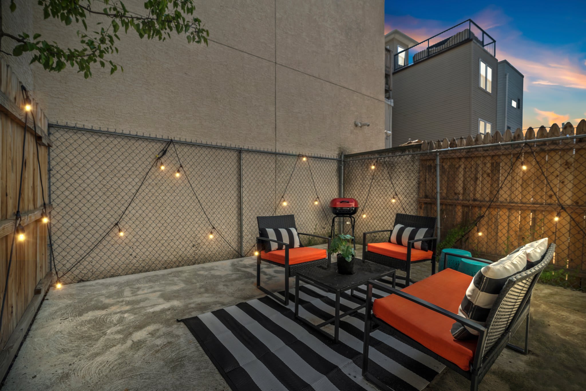 The private outdoor patio offers a serene space for evening relaxation, complete with comfortable seating and ambient string lights, ideal for a cozy night under the stars.