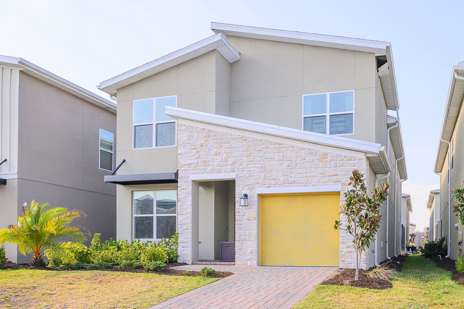 Elegant Exterior Featuring A Bold Yellow Garage Door And Stone Accents