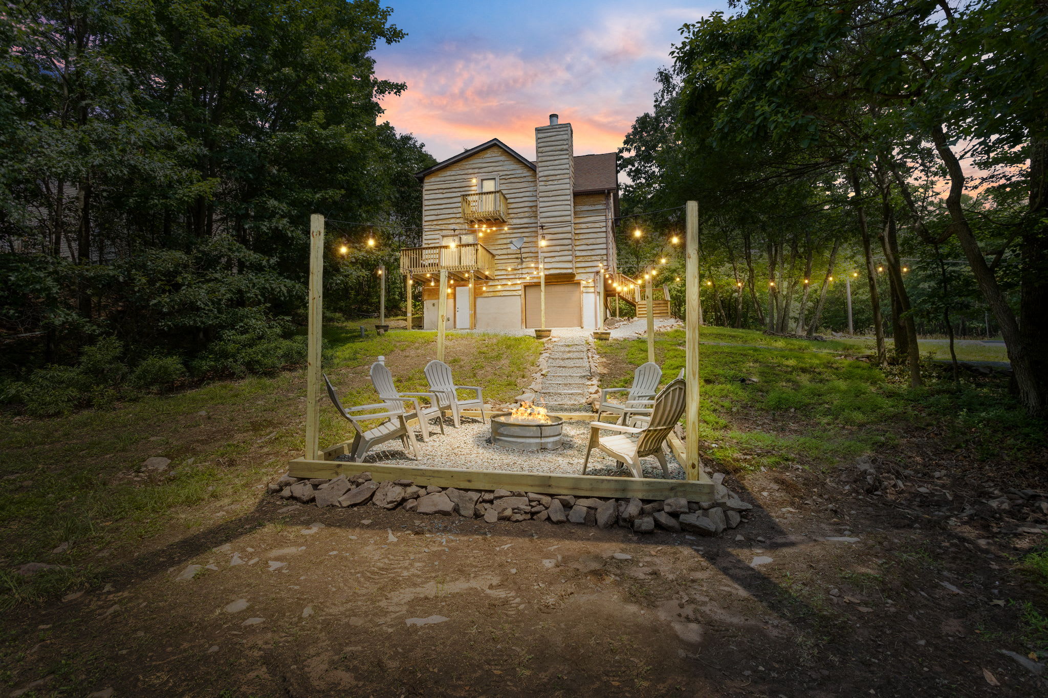 As the sun sets, the string lights illuminate this cozy outdoor fire pit area. Nestled against the scenic backdrop of a wooded hillside, it's the perfect place for late-night conversations and roasting marshmallows.