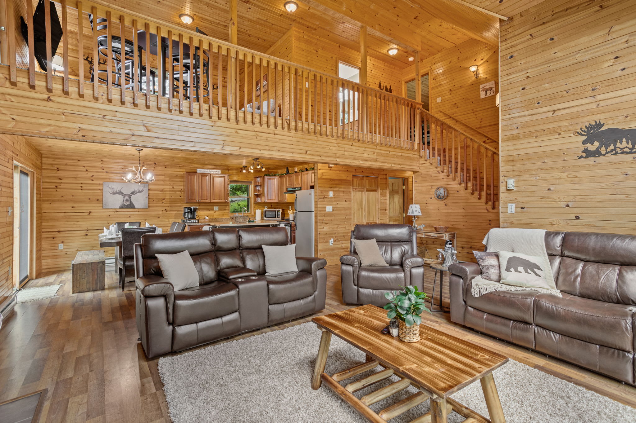 The open-concept layout, featuring rustic wood finishes and a cozy upstairs loft, creates a warm and inviting atmosphere perfect for gathering and unwinding.
