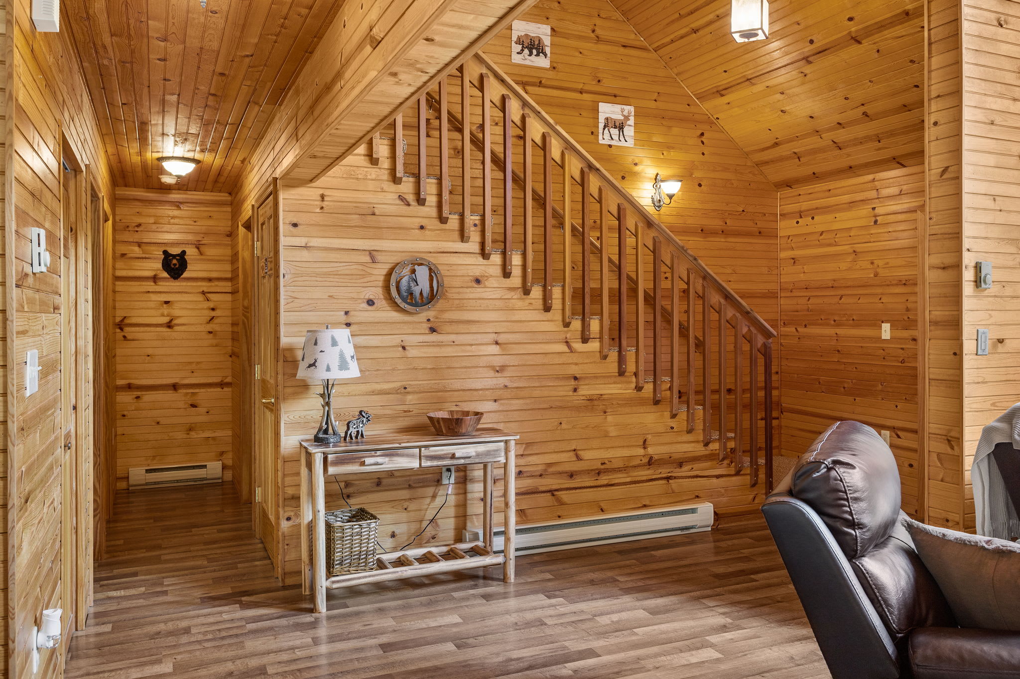 The natural wood staircase and walls bring a warm, cabin-like ambiance to the space, leading the way to the upper level of this charming retreat.