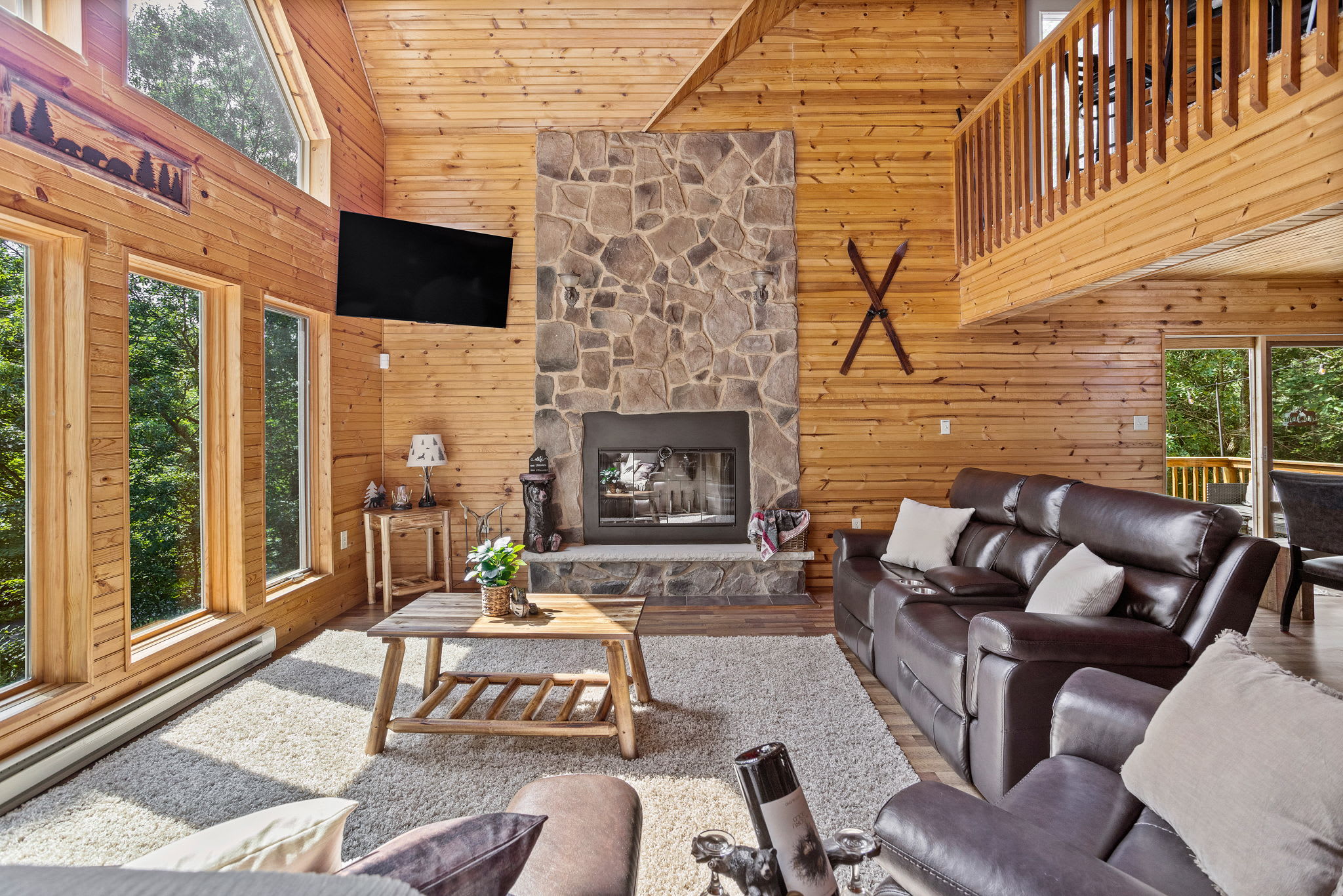 This spacious living room blends rustic charm with modern comfort. Enjoy the warmth of the stone fireplace while lounging in oversized leather recliners under vaulted wooden ceilings.