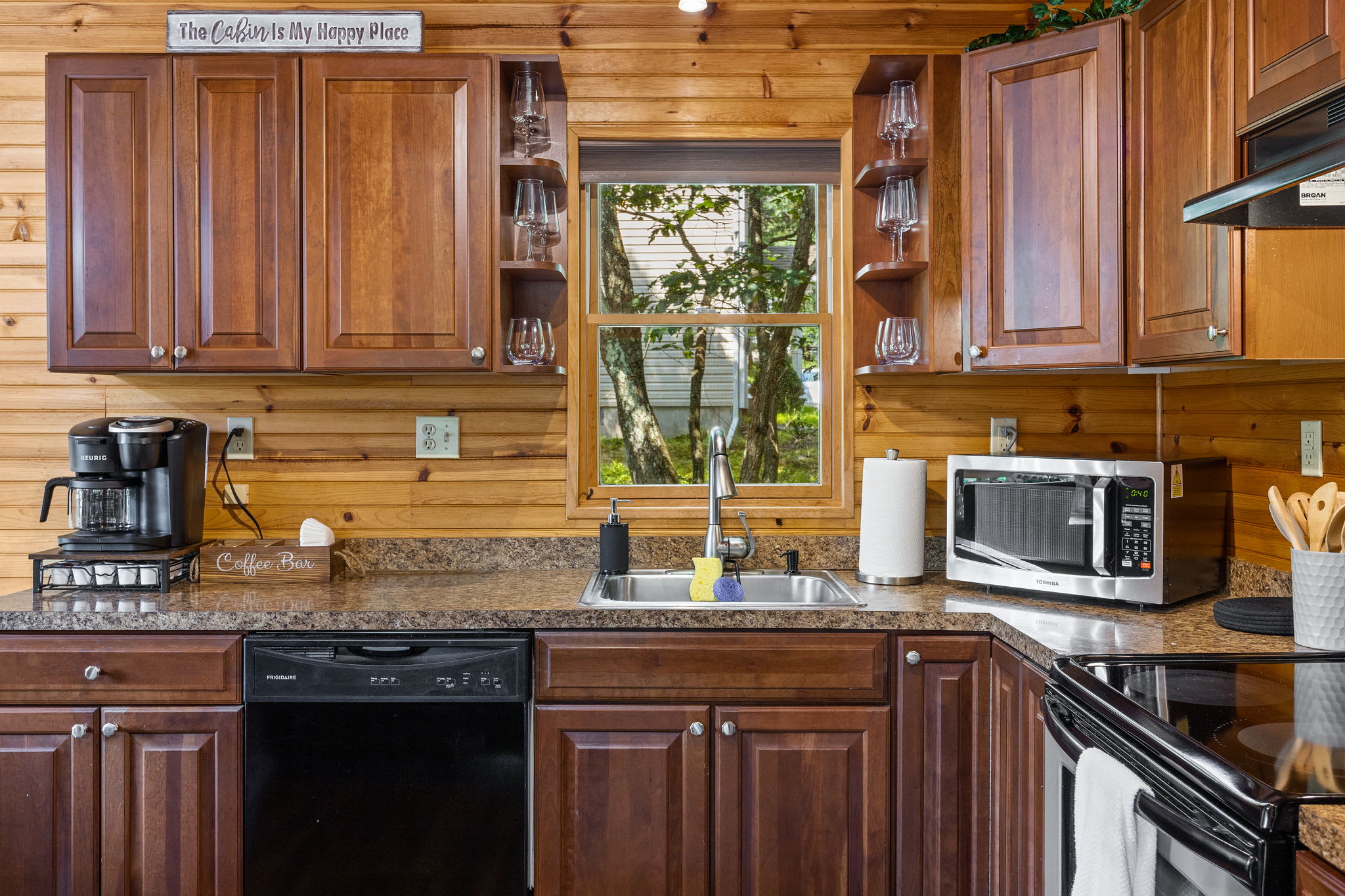 This well-stocked kitchen not only has everything you need to cook but also offers a scenic view through the window, bringing the beauty of nature inside.