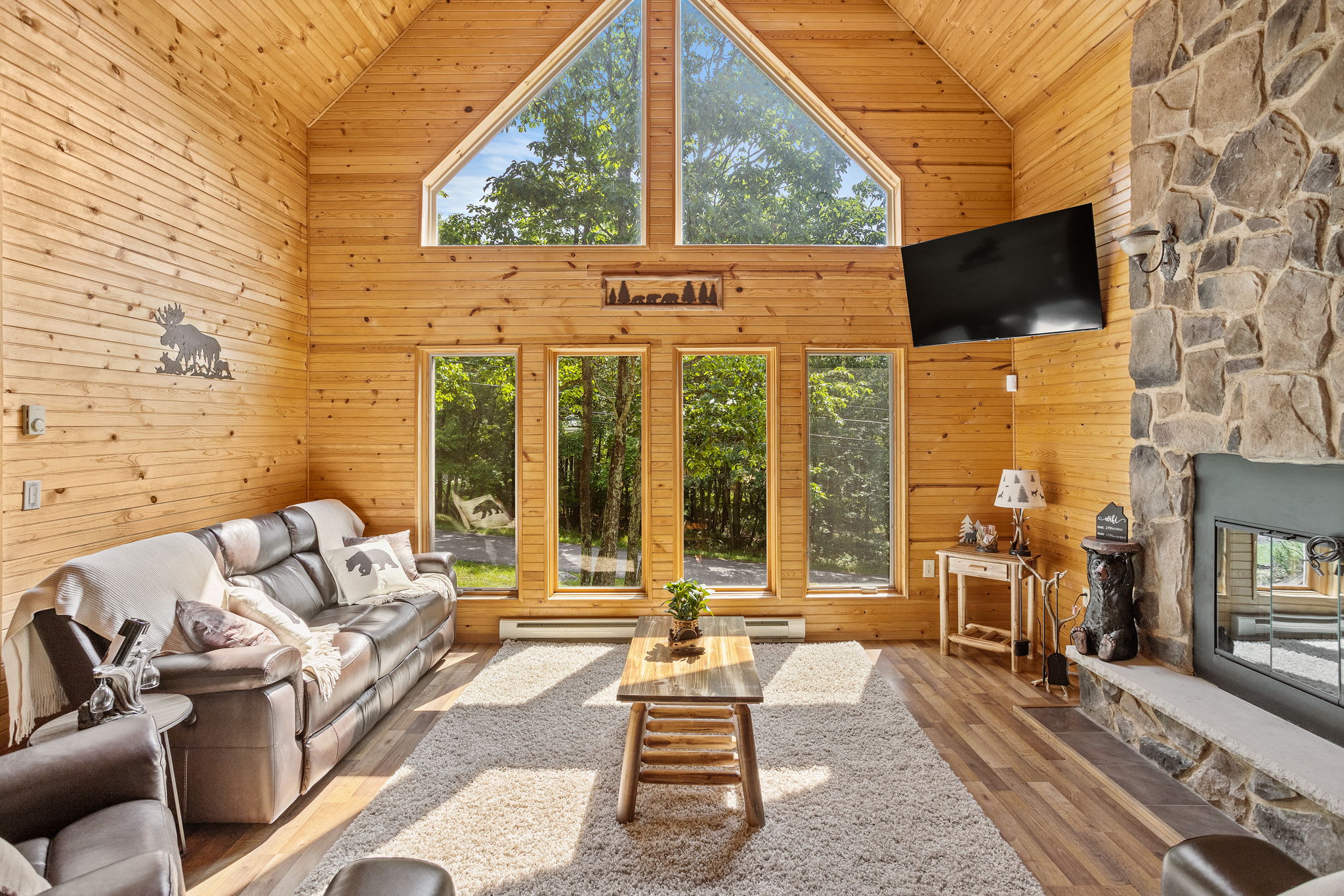 Floor-to-ceiling windows bring the outdoors in, flooding this cabin-style living room with natural light. The perfect spot to sip your morning coffee and soak in the tranquility.