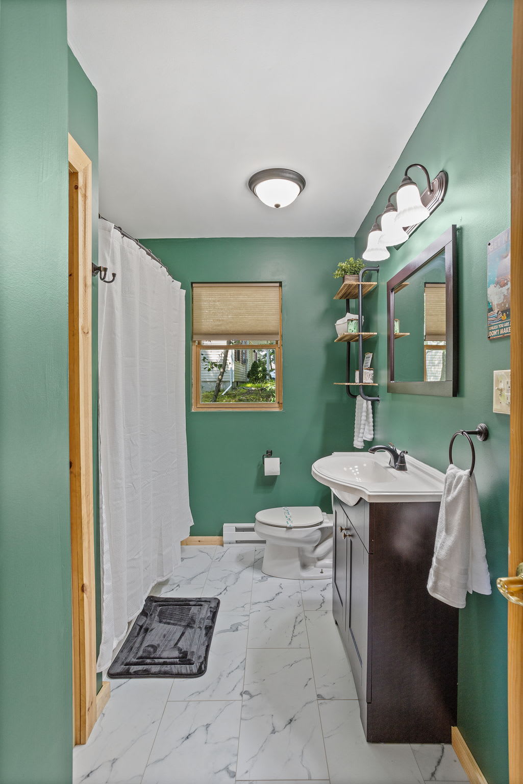 This beautifully designed bathroom features a calming green color palette, a sleek white vanity, and a bright, airy layout that adds a spa-like touch.