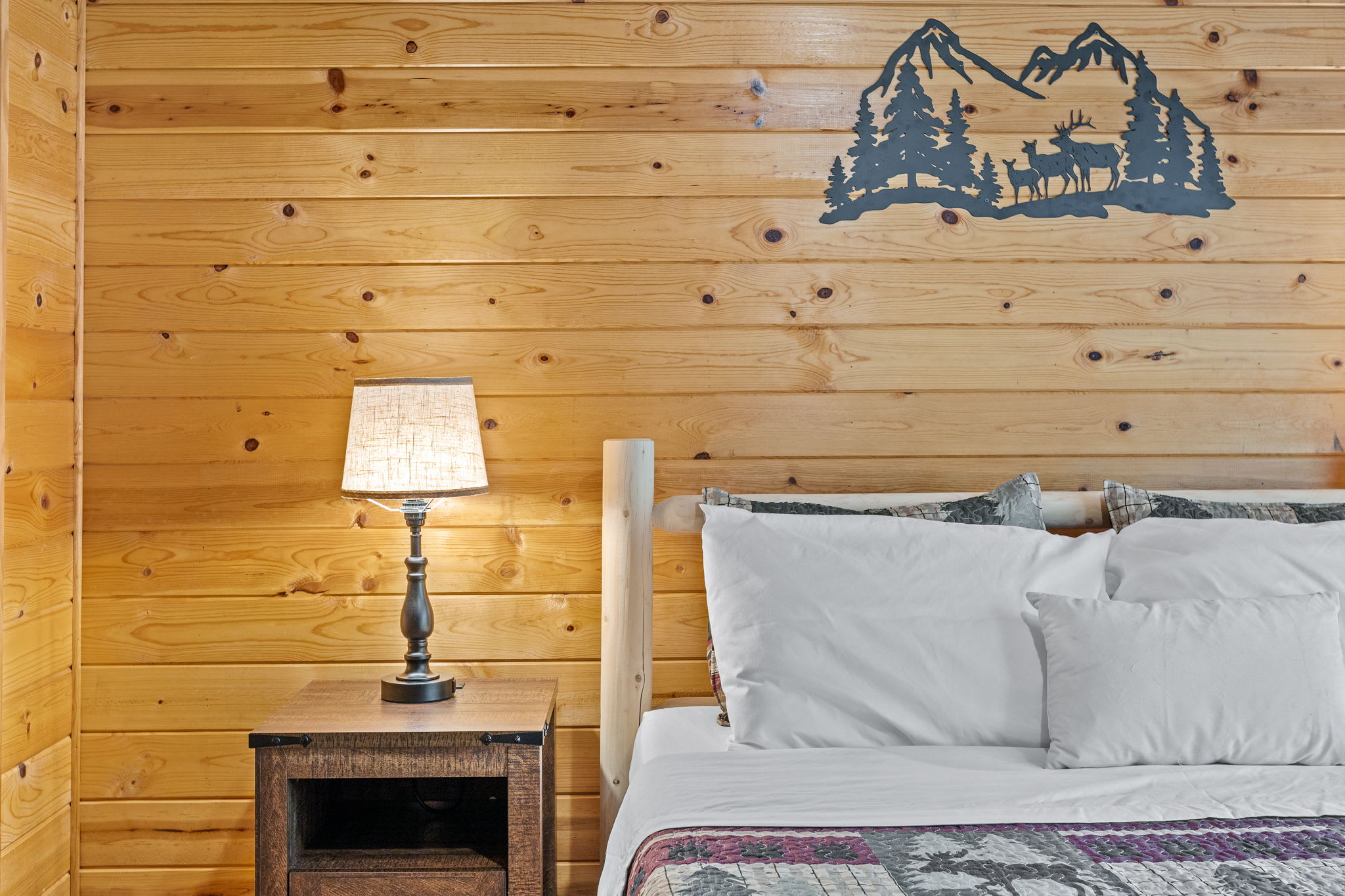 The soft glow of the bedside lamps and the mountain-themed wall décor create a warm, rustic ambiance for the perfect night’s sleep.