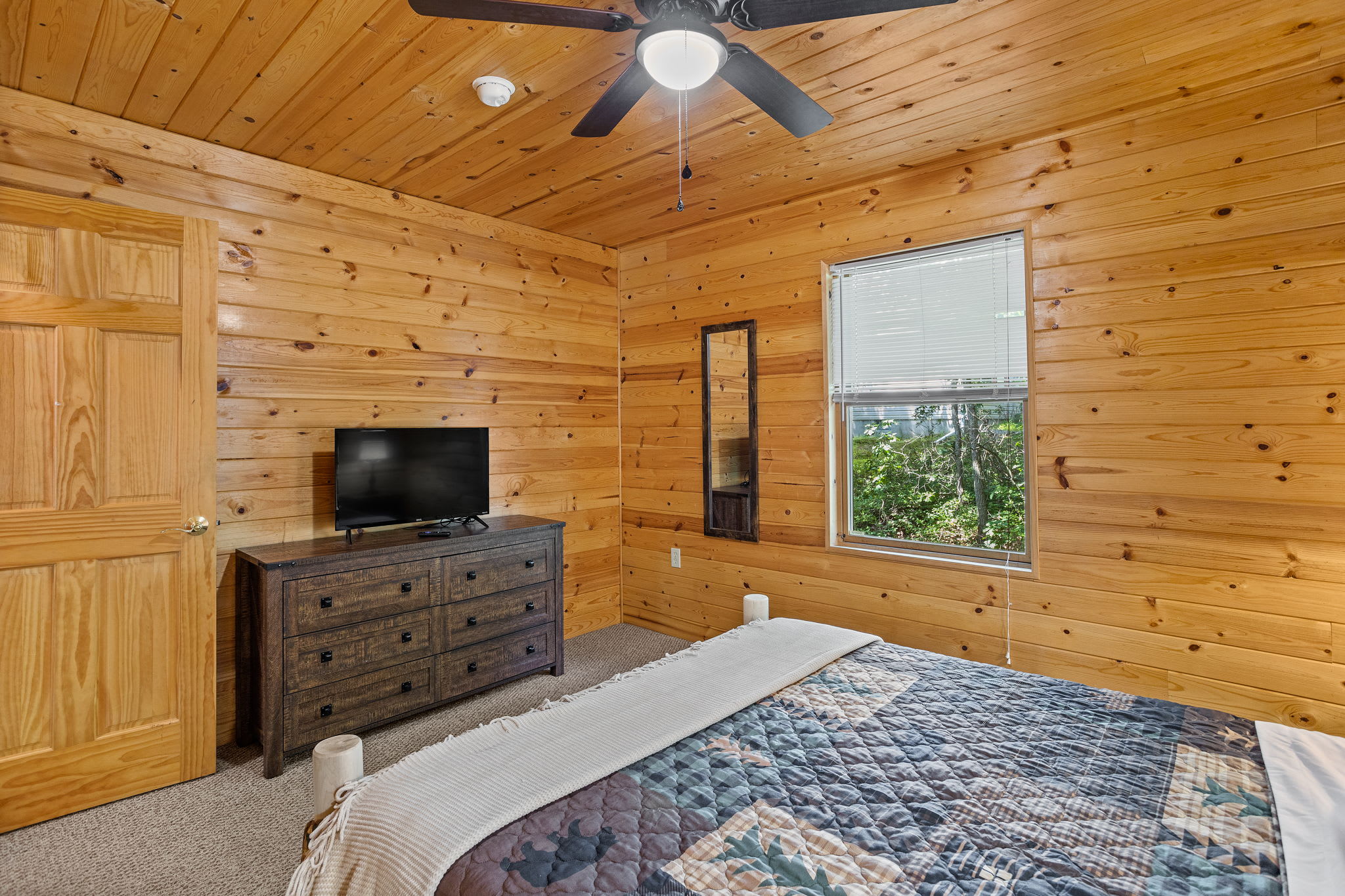 Enjoy a peaceful night’s sleep in this charming space, complete with a dresser, TV, and a window that brings in natural light and a view of the outdoors.