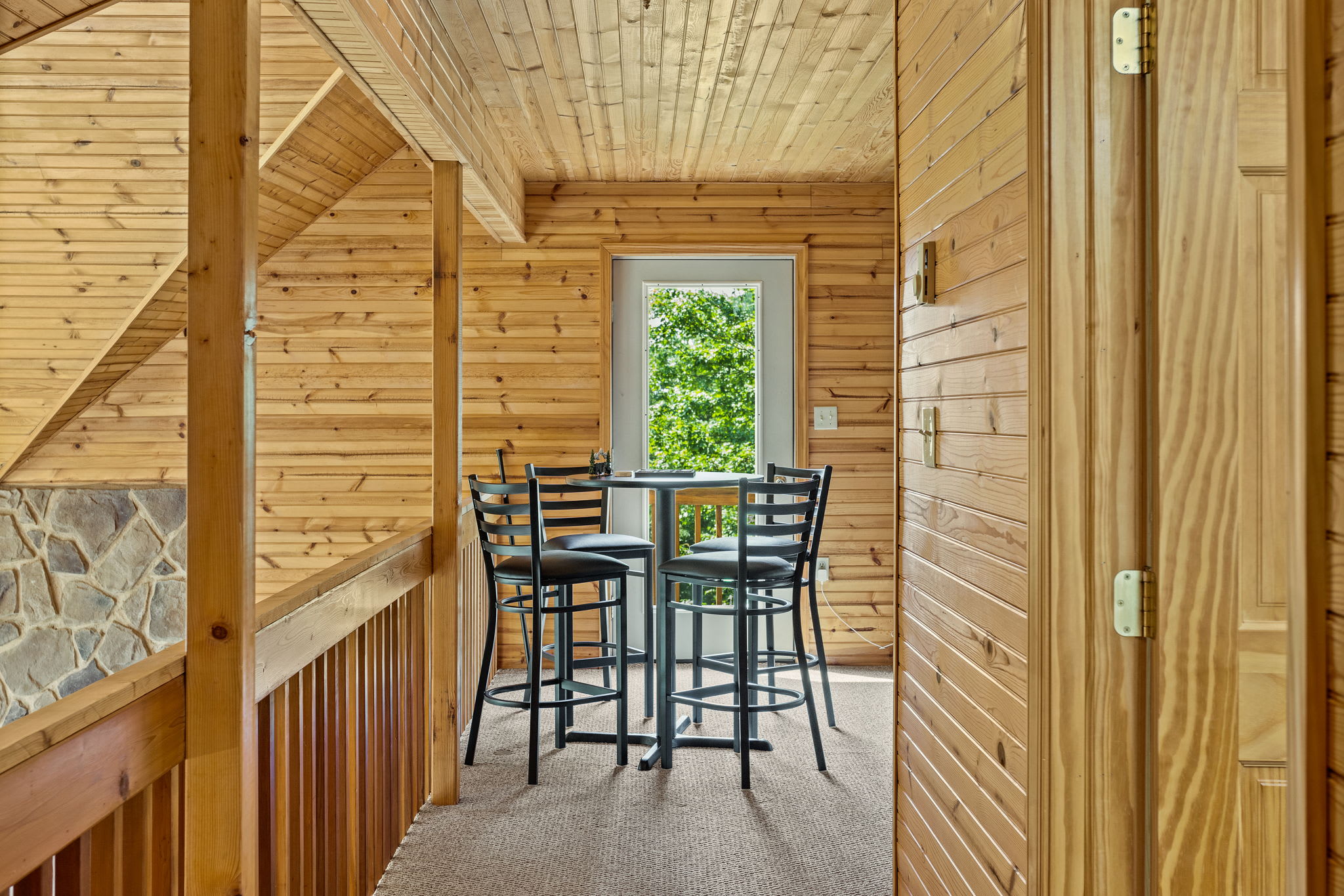 This charming loft space features a high-top table, perfect for morning coffee while enjoying peaceful views of the surrounding nature.