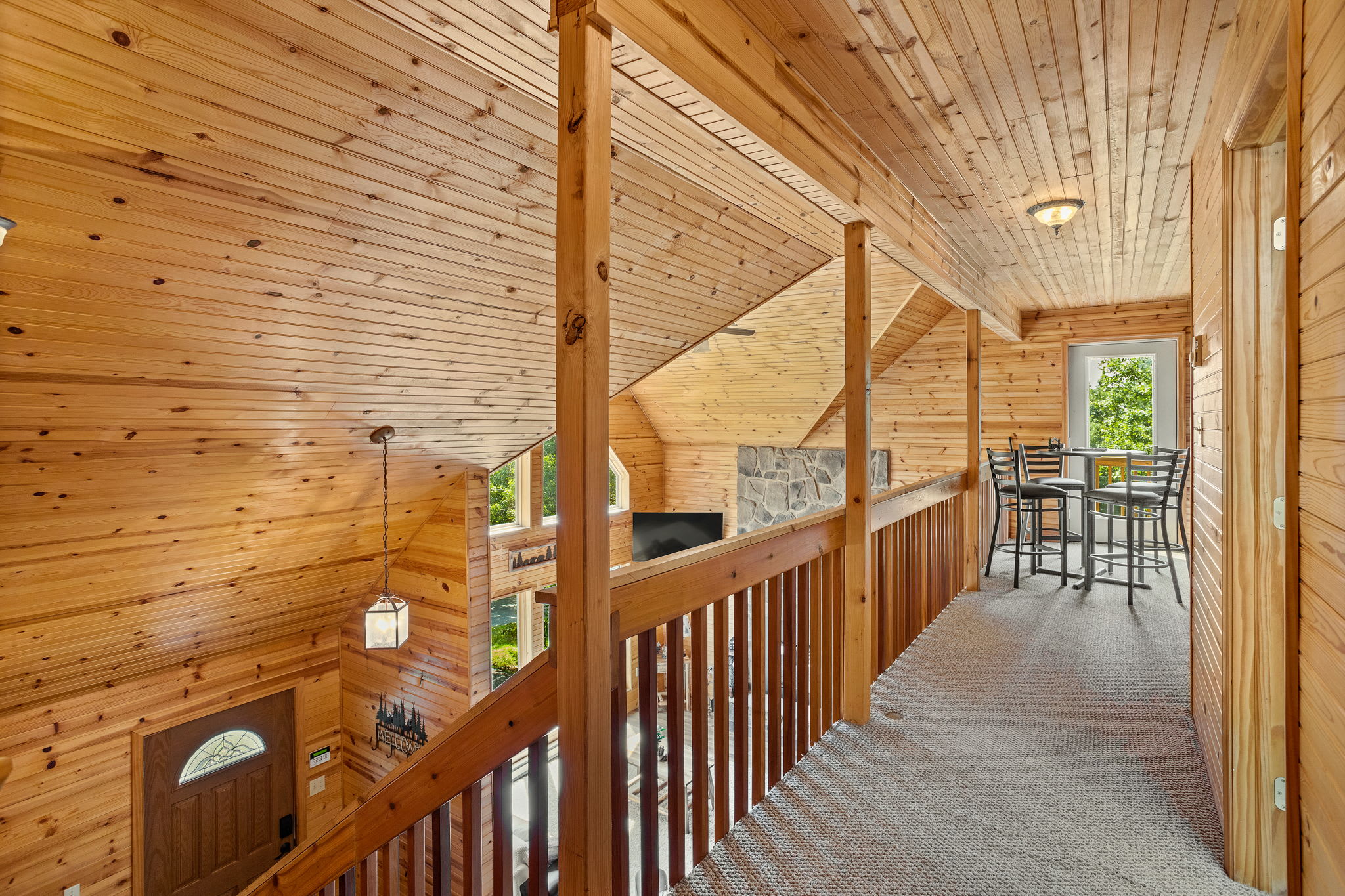 A bright and spacious upper-level walkway leads to a cozy seating area, offering stunning views of the main living space below.