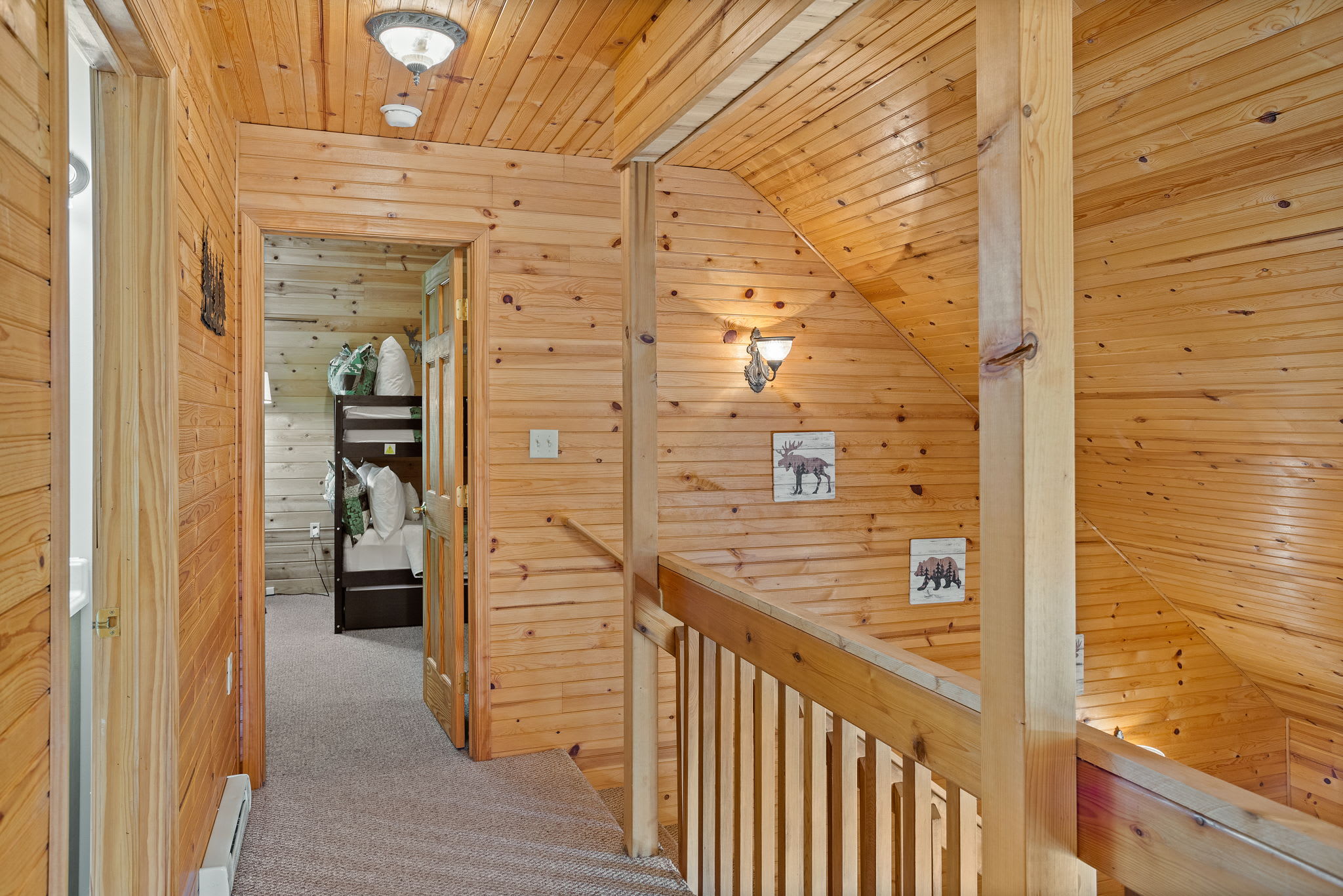 A beautifully designed hallway with rustic wood finishes leads to a charming bunk room, offering a cozy retreat for guests.