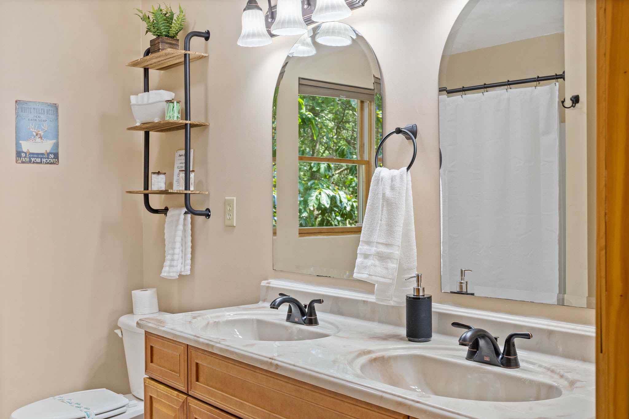 Featuring a sleek double sink, open shelving, and warm natural tones, this bathroom is both stylish and functional for guests.