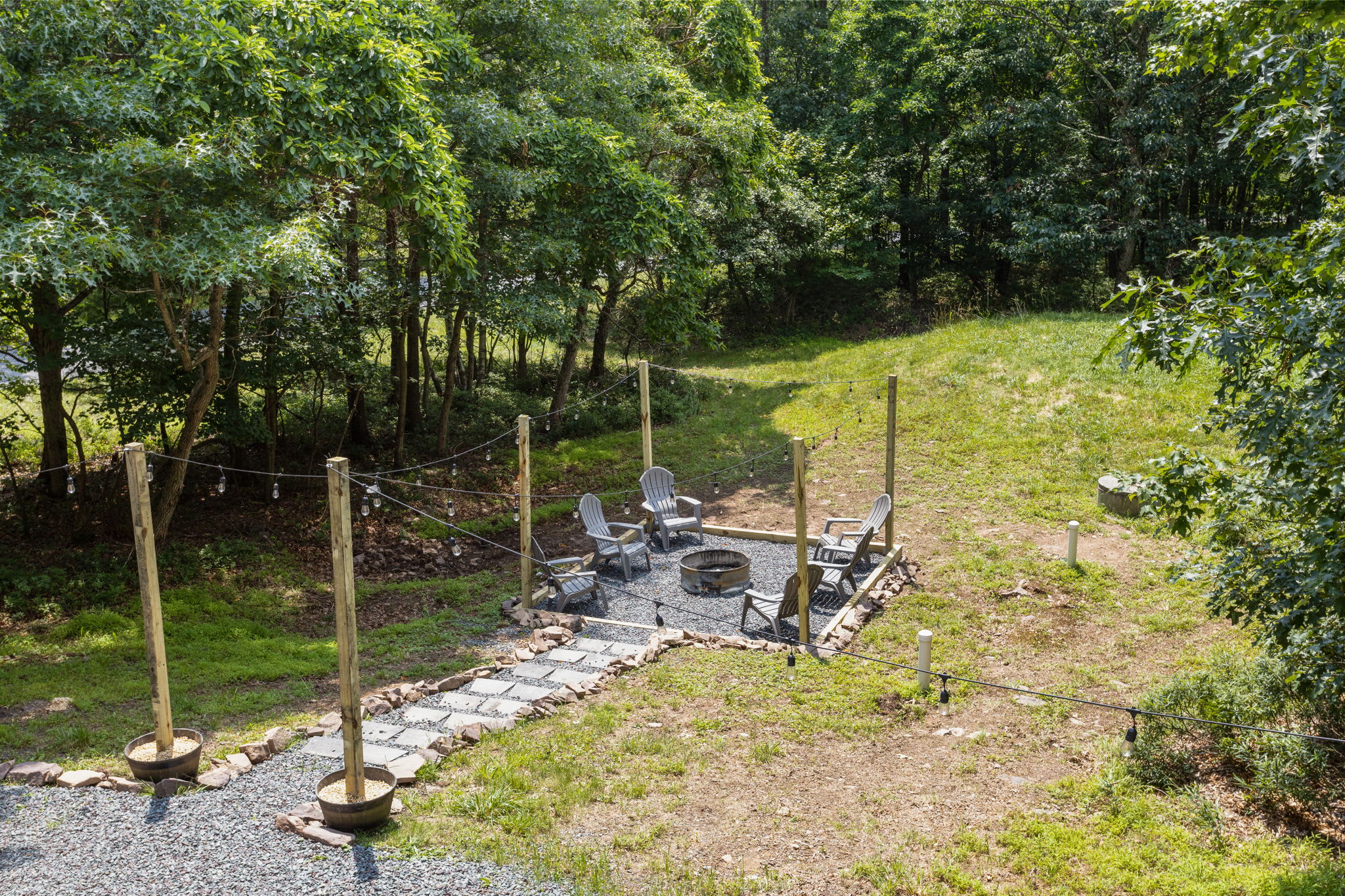 A peaceful backyard retreat with a stone pathway leading to a cozy fire pit, surrounded by nature.
