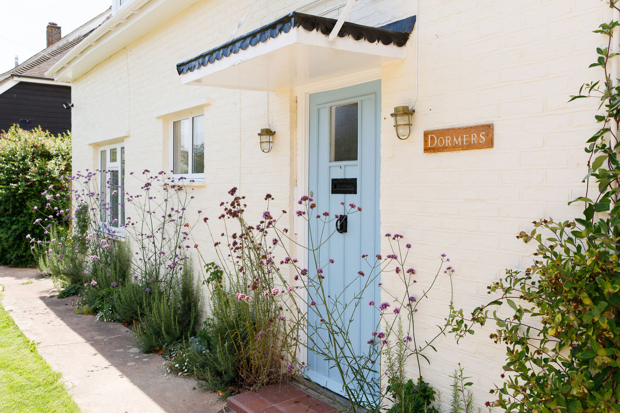Pretty blue front door with flowering plants.