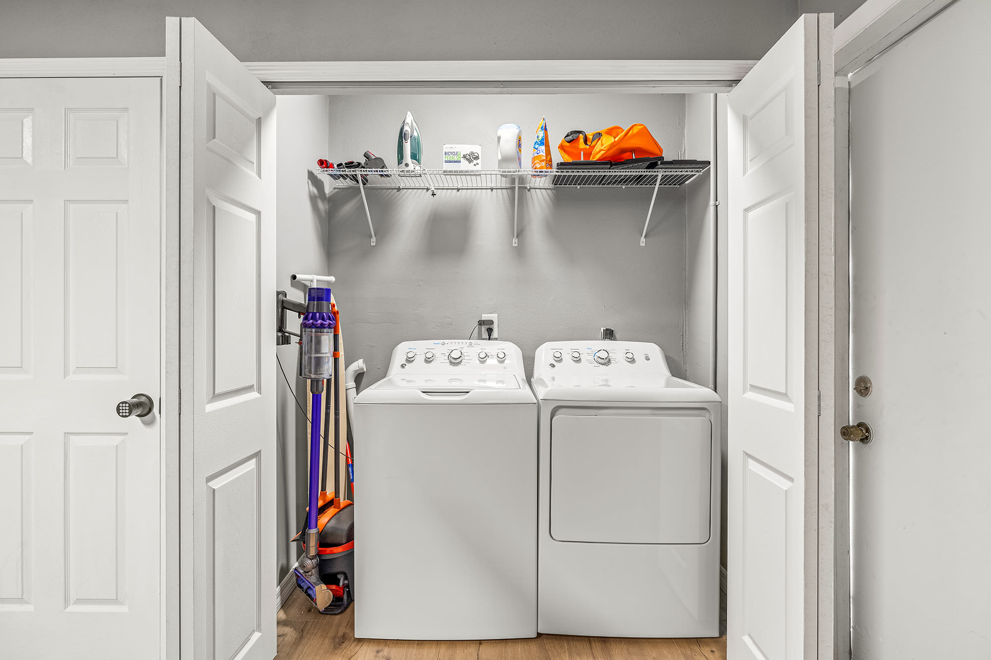 In unit washer and dryer with Dyson Vacuum, laundry detergent, and iron.