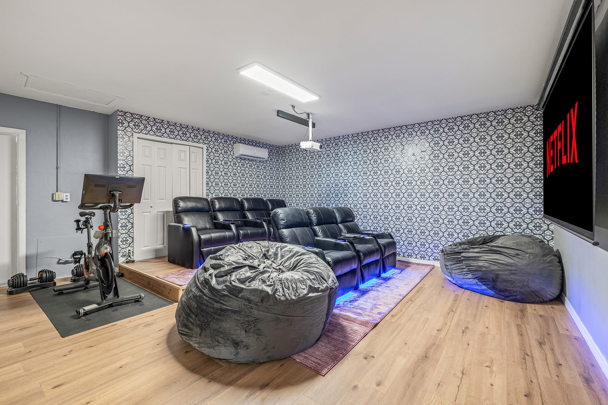 In-home movie theater- sit back relax in the luxury reclining seats or a bean bag- This room also features a Peloton, adjustable weights, and yoga mat!