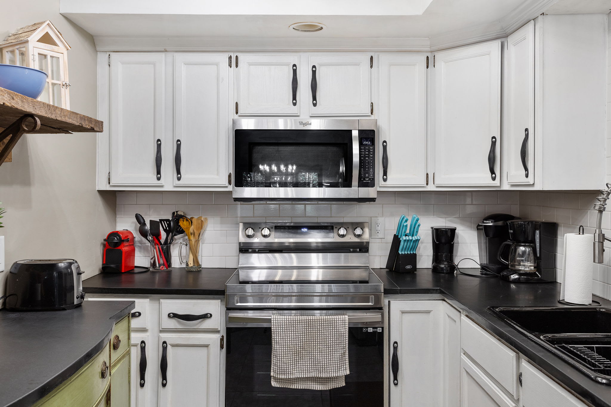 Kitchen with Modern Touches – A mix of white cabinetry, dark countertops, and charming details