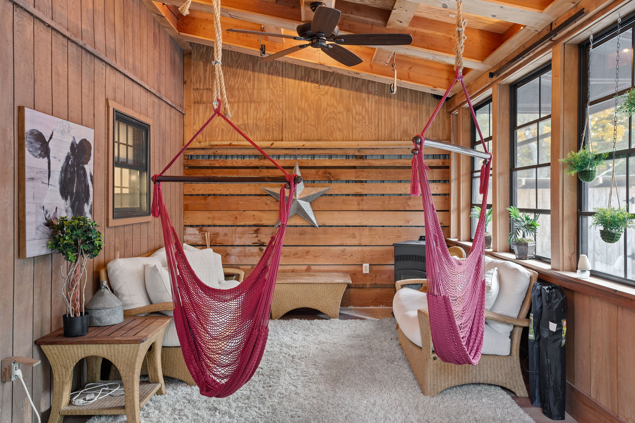 A pair of vibrant hammock chairs adds a playful touch, inviting you to unwind in this airy, wood-paneled retreat.