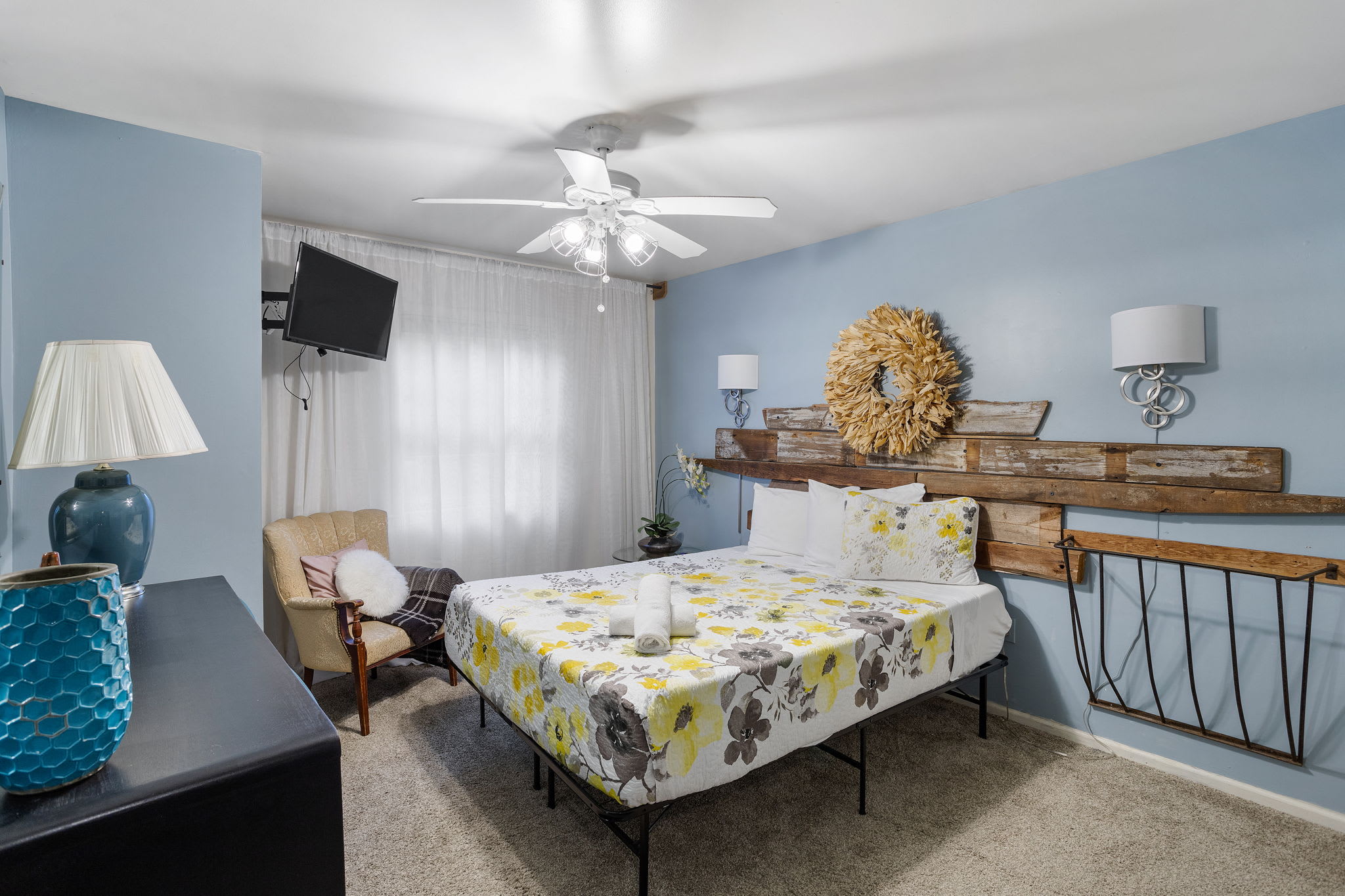 A reclaimed wood headboard and rustic wreath bring subtle farmhouse charm to this cozy bedroom.