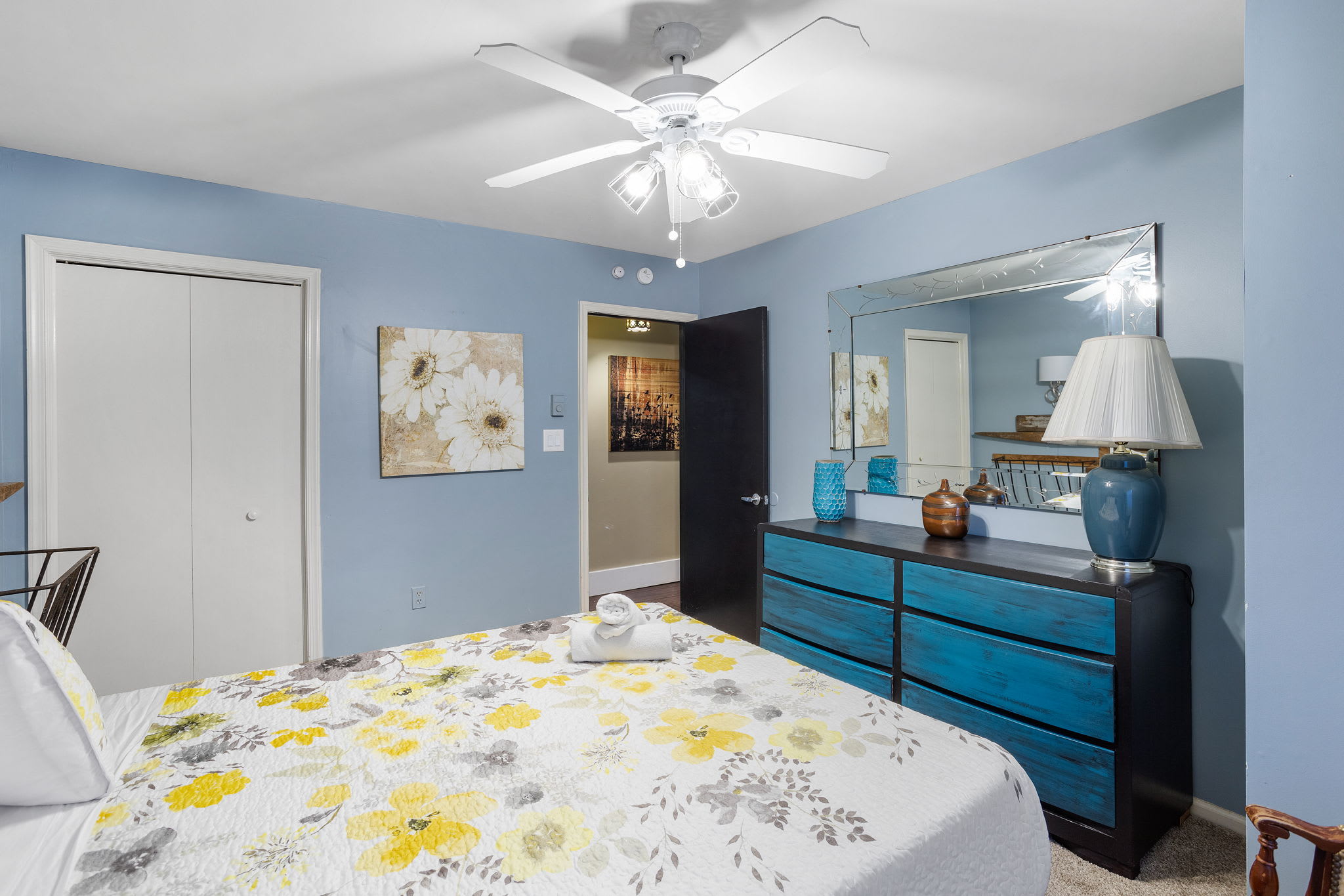 Soft blue walls and a vibrant floral bedspread create a refreshing, cheerful vibe for a restful night.