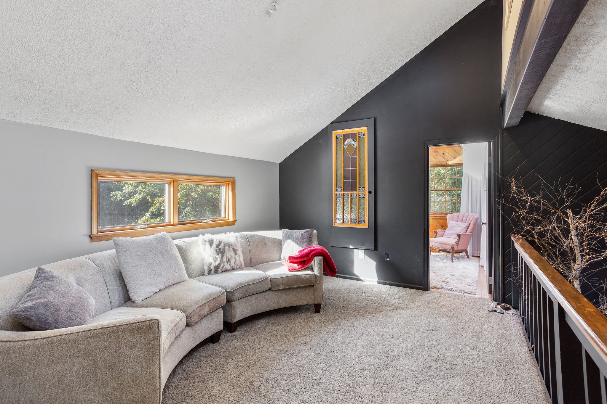 A plush curved sofa invites you to lounge in this airy loft, where a black accent wall adds modern contrast.