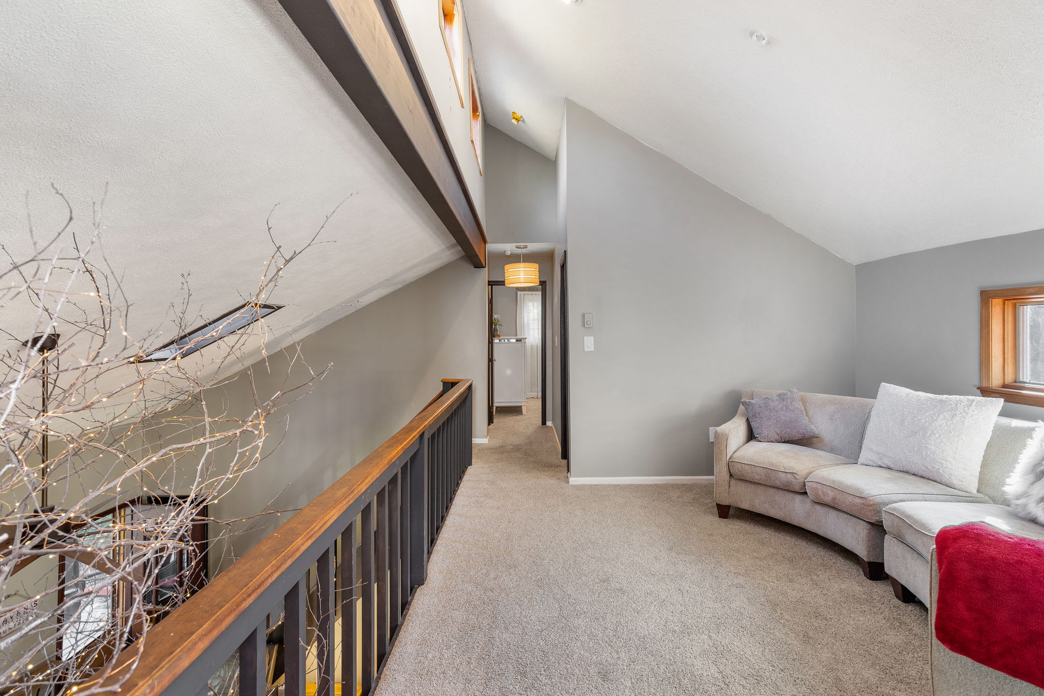 Natural light streams through the wide window, highlighting the room’s vaulted ceilings and soft carpeting.