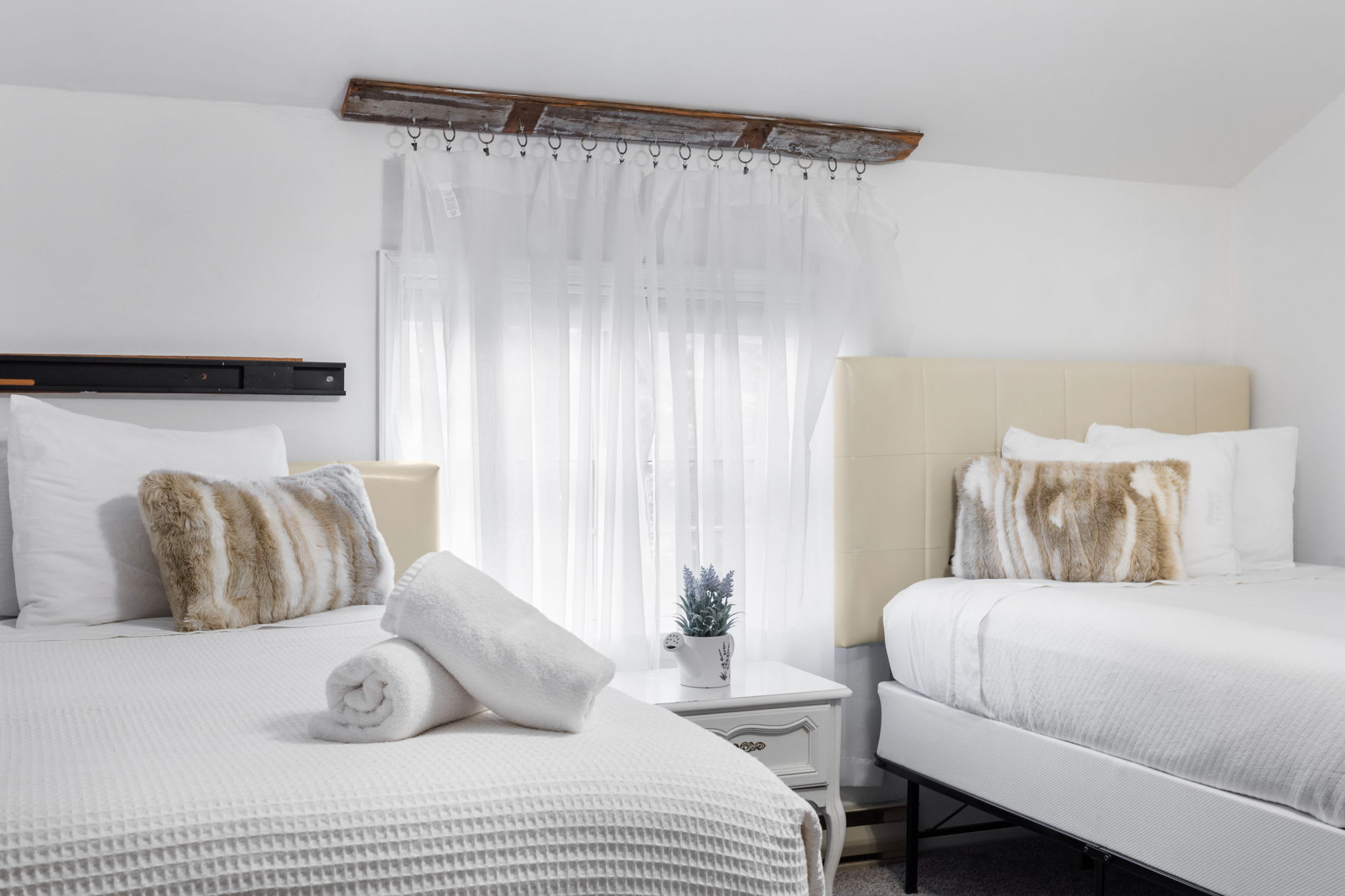 Sheer curtains drape from a rustic wood rod, allowing natural light to softly illuminate the room.