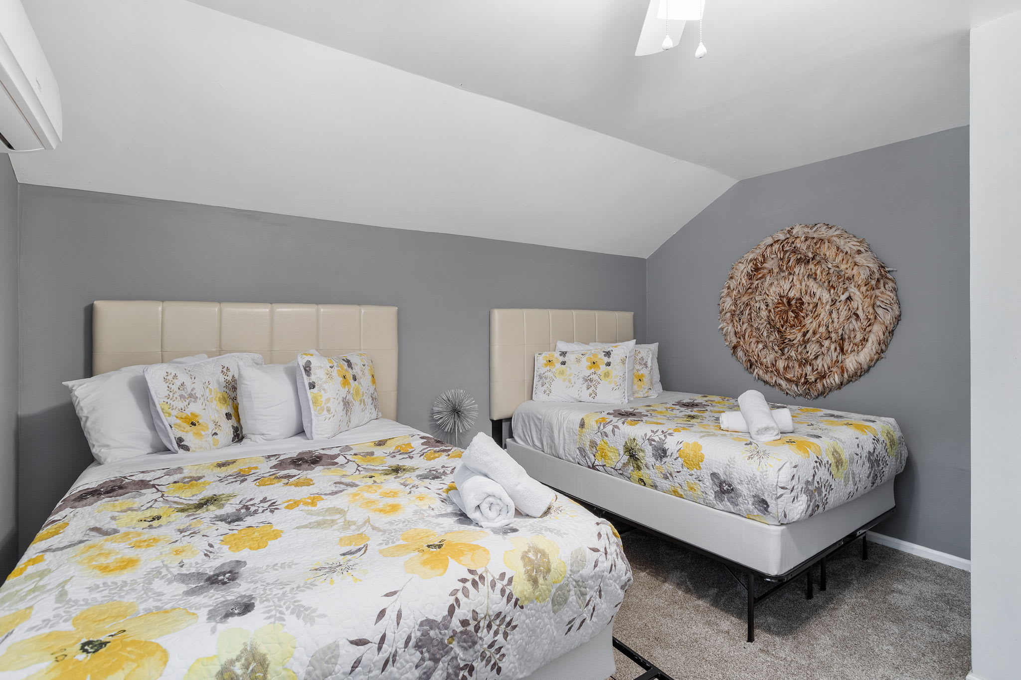 Two plush beds with floral bedding stand against soft gray walls, offering a cheerful yet calming retreat.