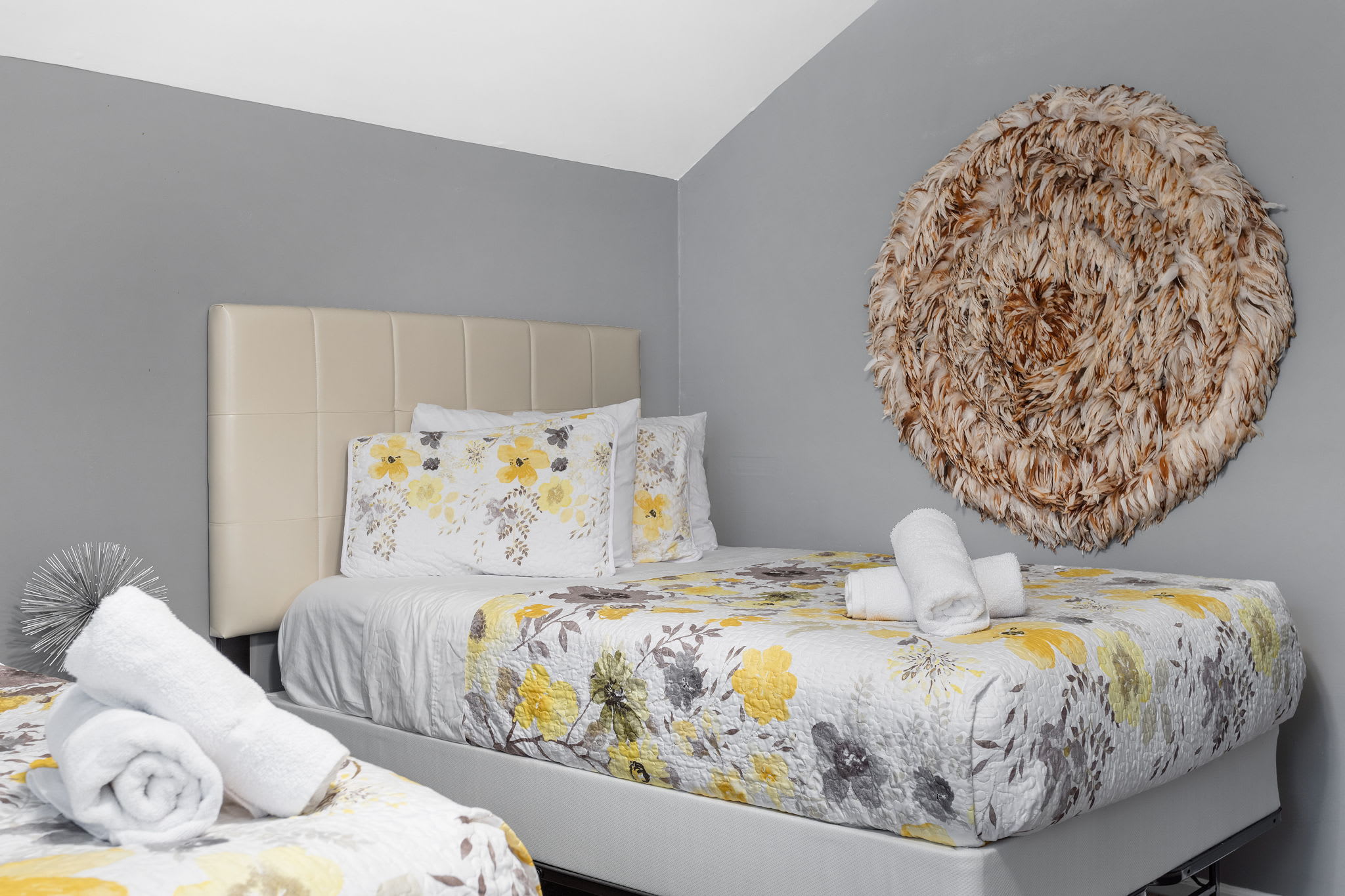 A closer look at the vibrant comforters and feather wall art showcases the room’s playful mix of texture and color.