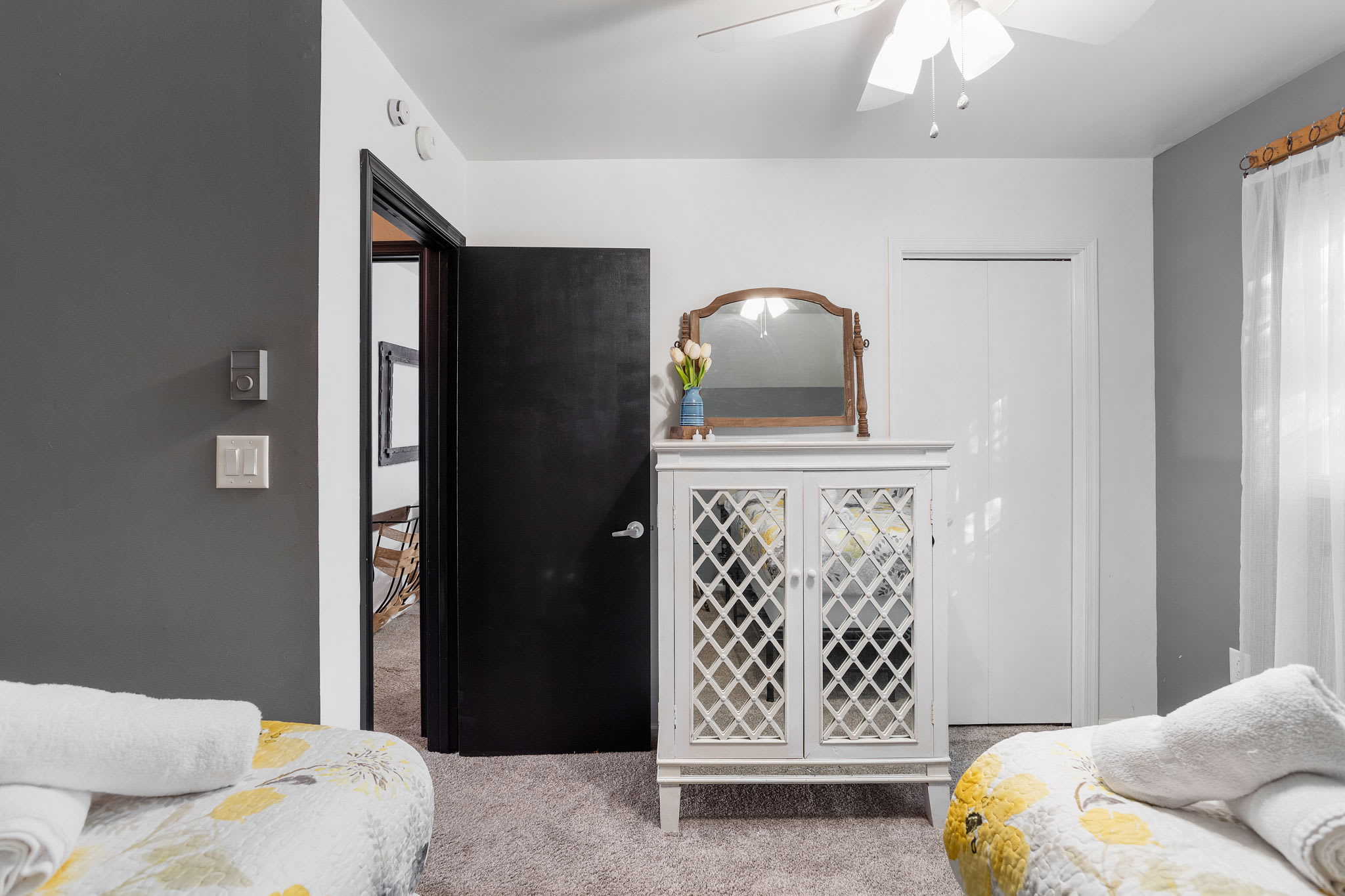 A white lattice-front dresser and mirror add a touch of classic charm, blending seamlessly with the room’s modern palette.