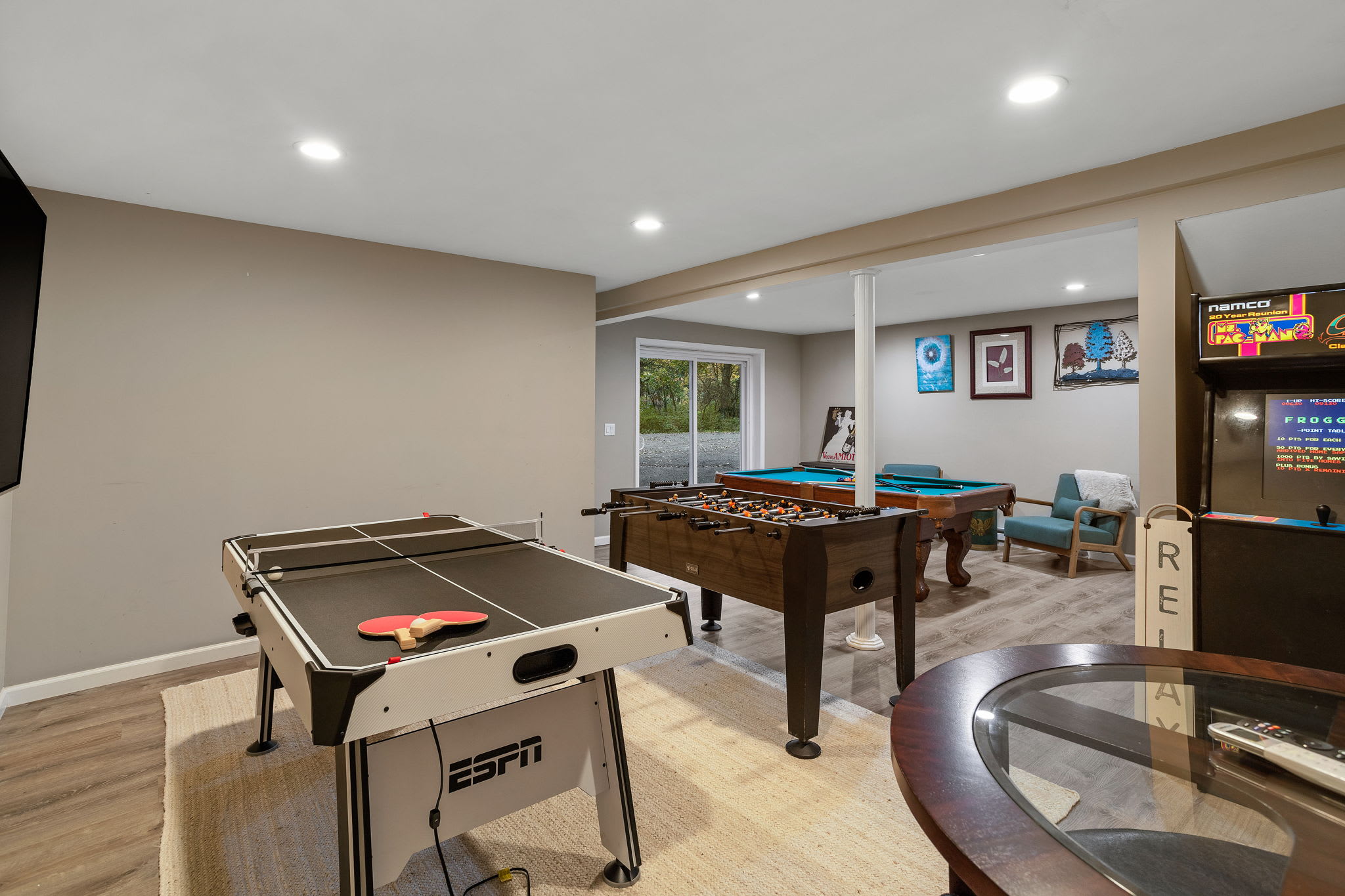 A wide shot showcases the game tables and sliding door, highlighting the seamless flow between indoor excitement and outdoor scenery.