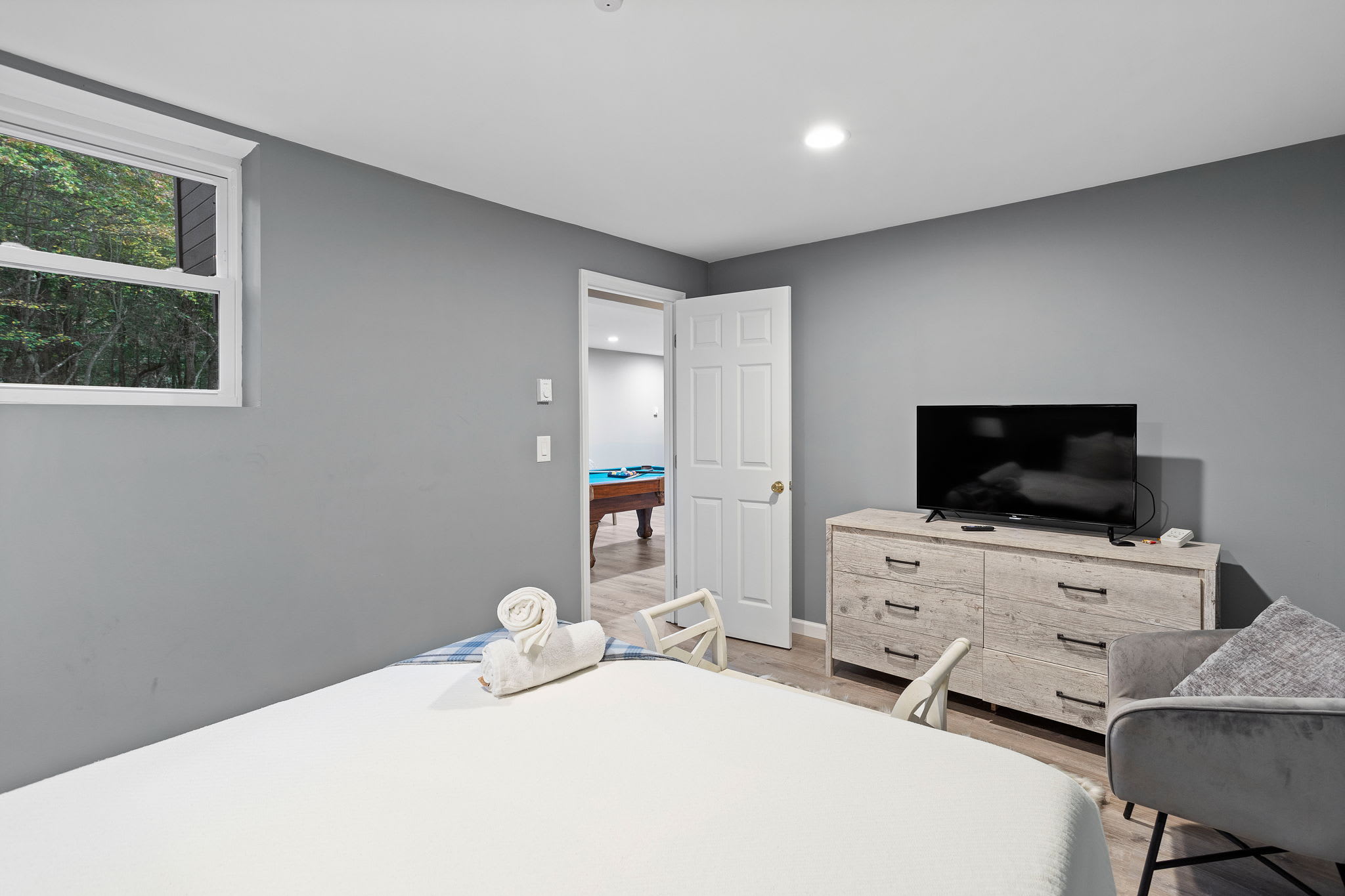 From the bed, you can see the game room just beyond, while a sleek dresser and TV offer easy entertainment options.