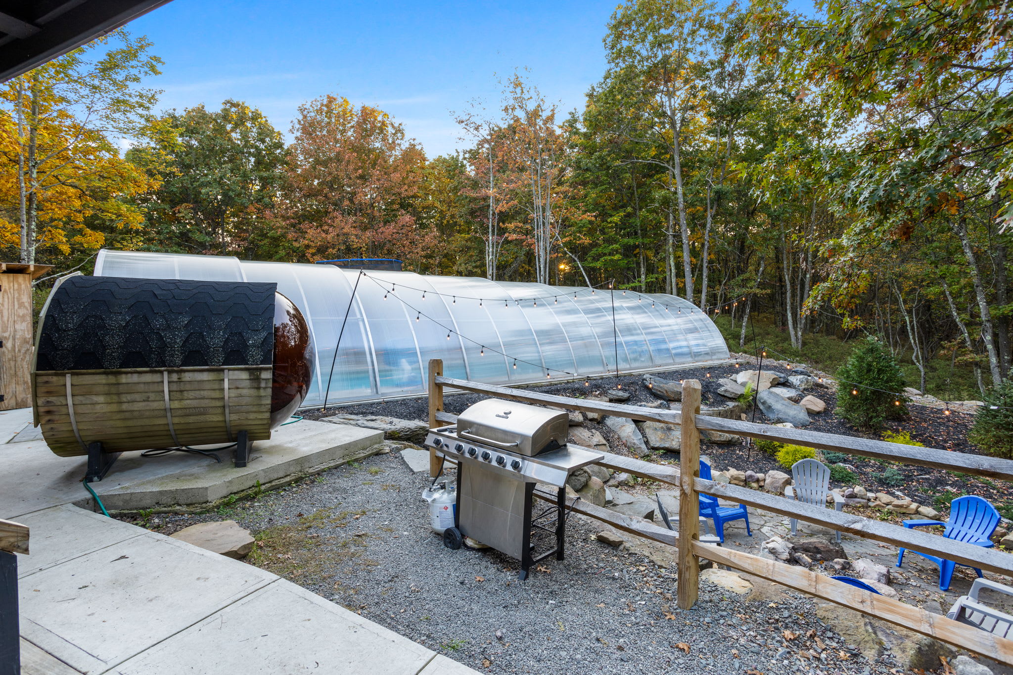 A barrel sauna and grill area overlook the fire pit, seamlessly blending outdoor leisure with woodland serenity.
