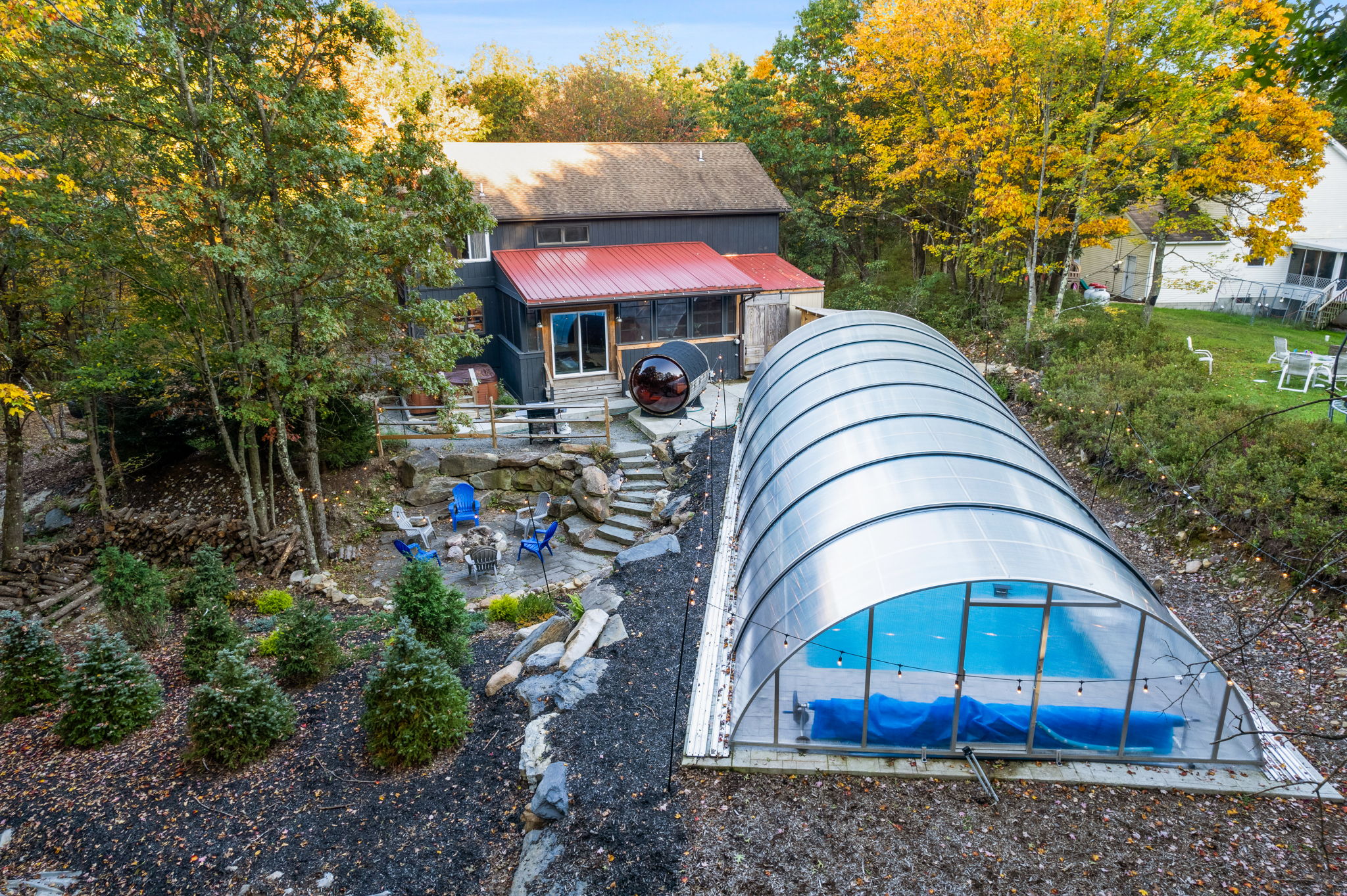 From above, the enclosed pool stands out as a year-round luxury, tucked beside the rustic charm of the main house.