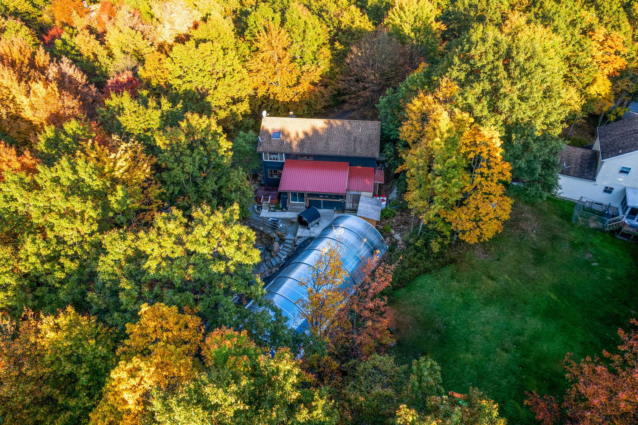 An aerial view reveals the home nestled among vibrant autumn leaves, offering a secluded retreat in the heart of nature.