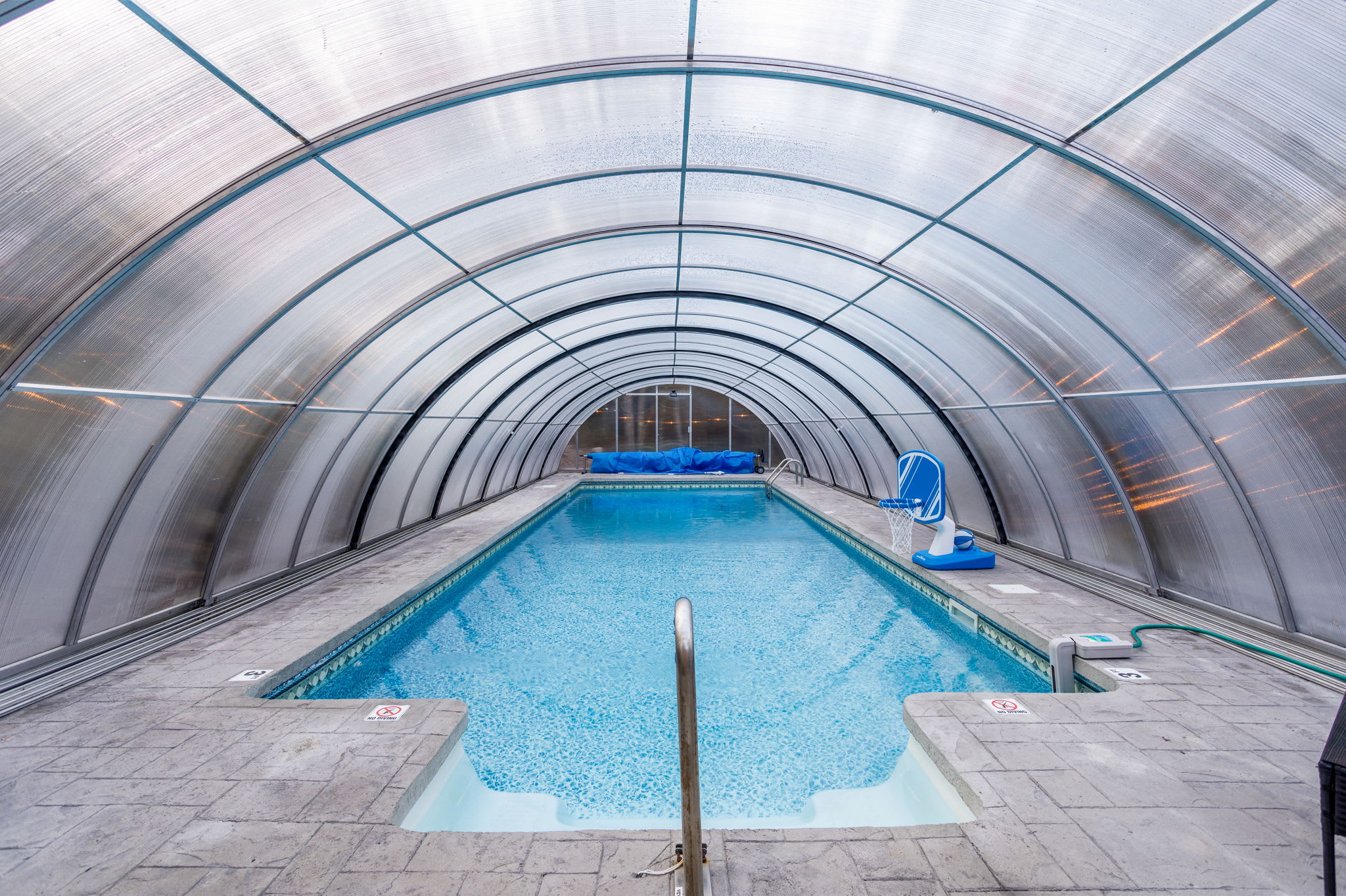 Inside the pool enclosure, crystal-clear water contrasts beautifully with the lush greenery outside. Dip in for a relaxing swim or simply float and enjoy the view.