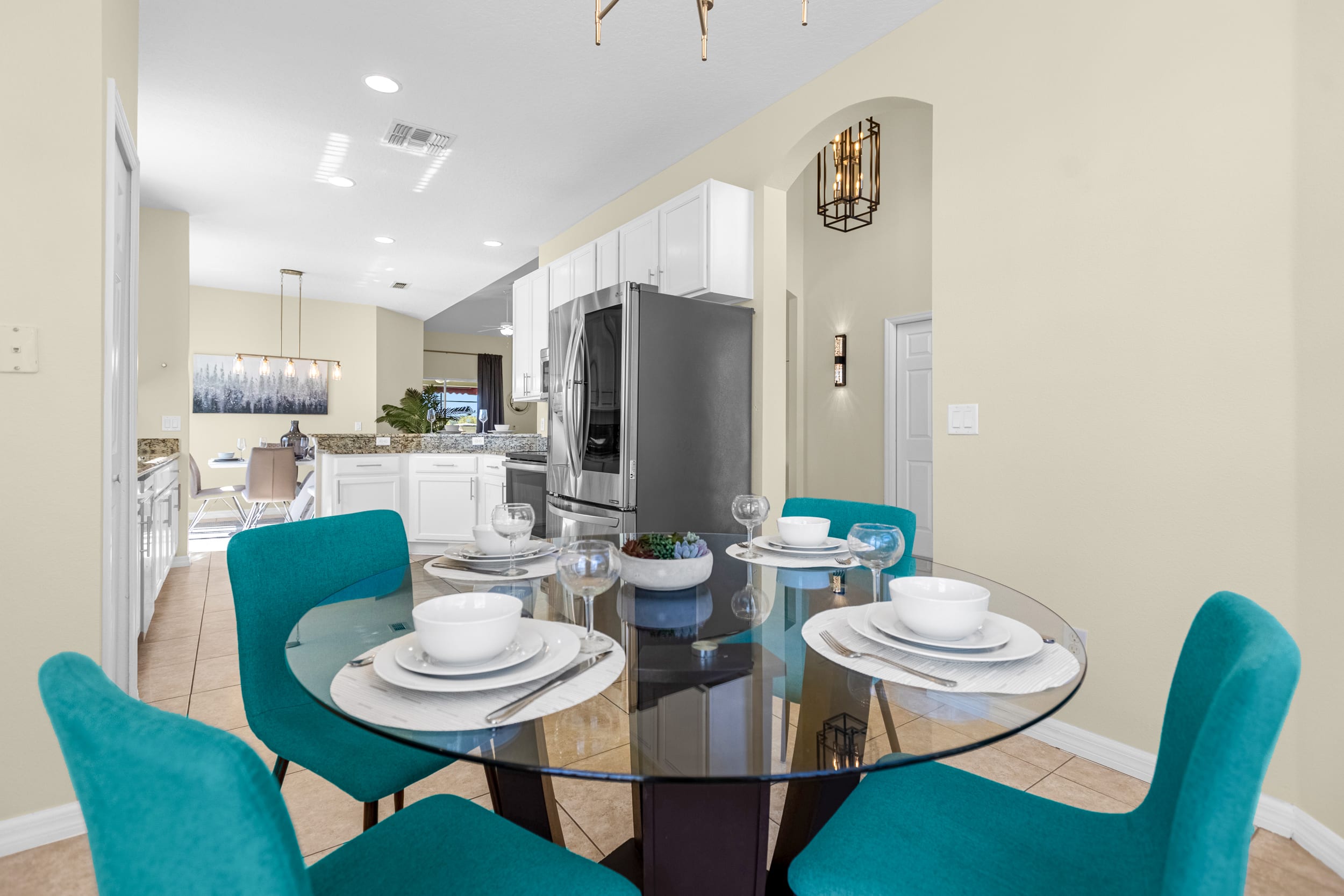Sleek Dining Area With Glass Table And Vibrant Teal Chairs